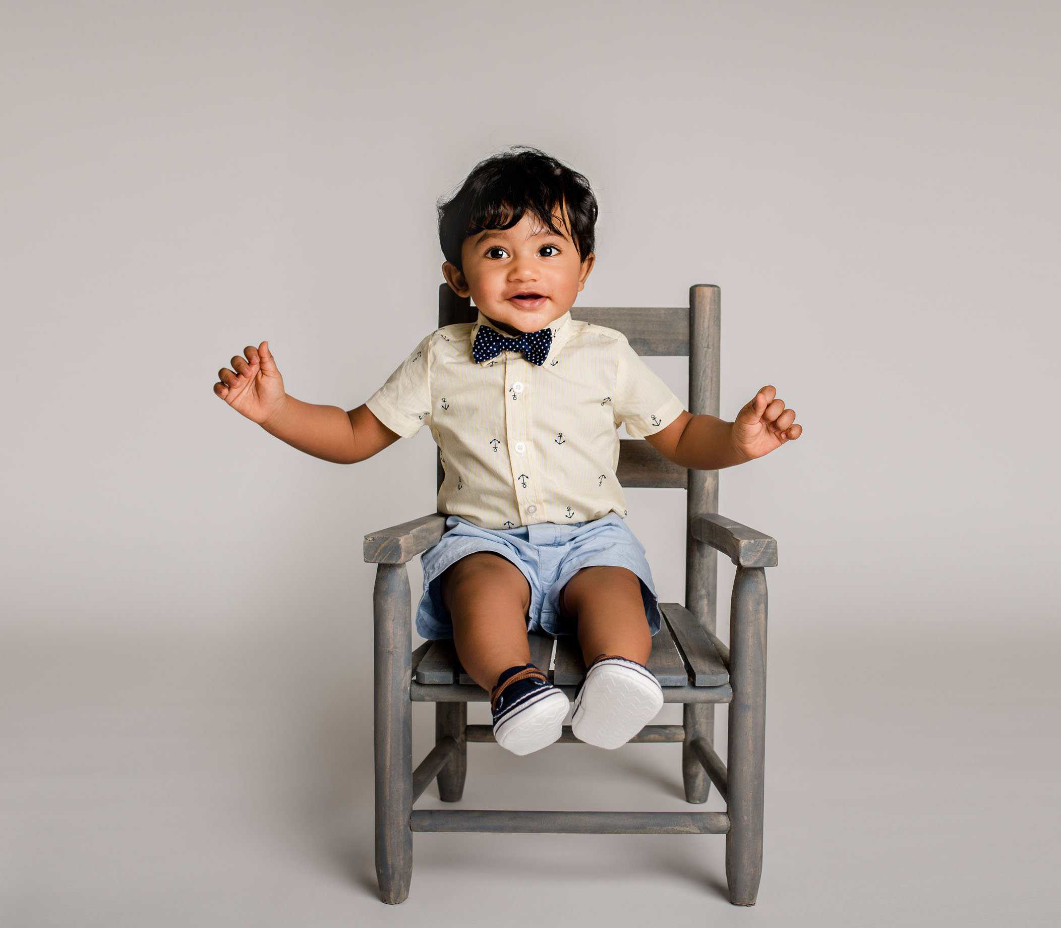8 mo old boy sitting in small chair smiling