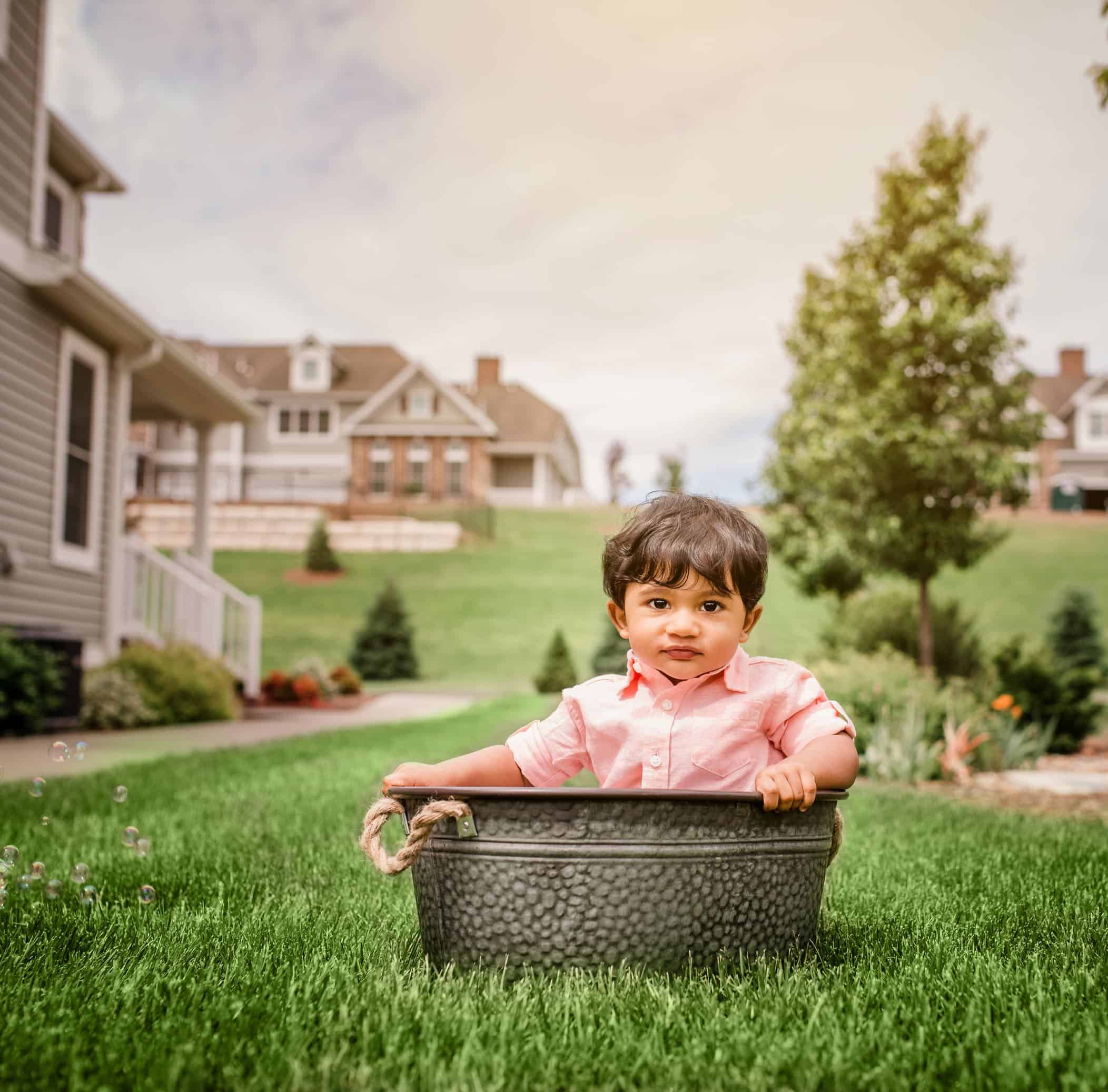 8 mo old indian boy sitting in tin tub in garden