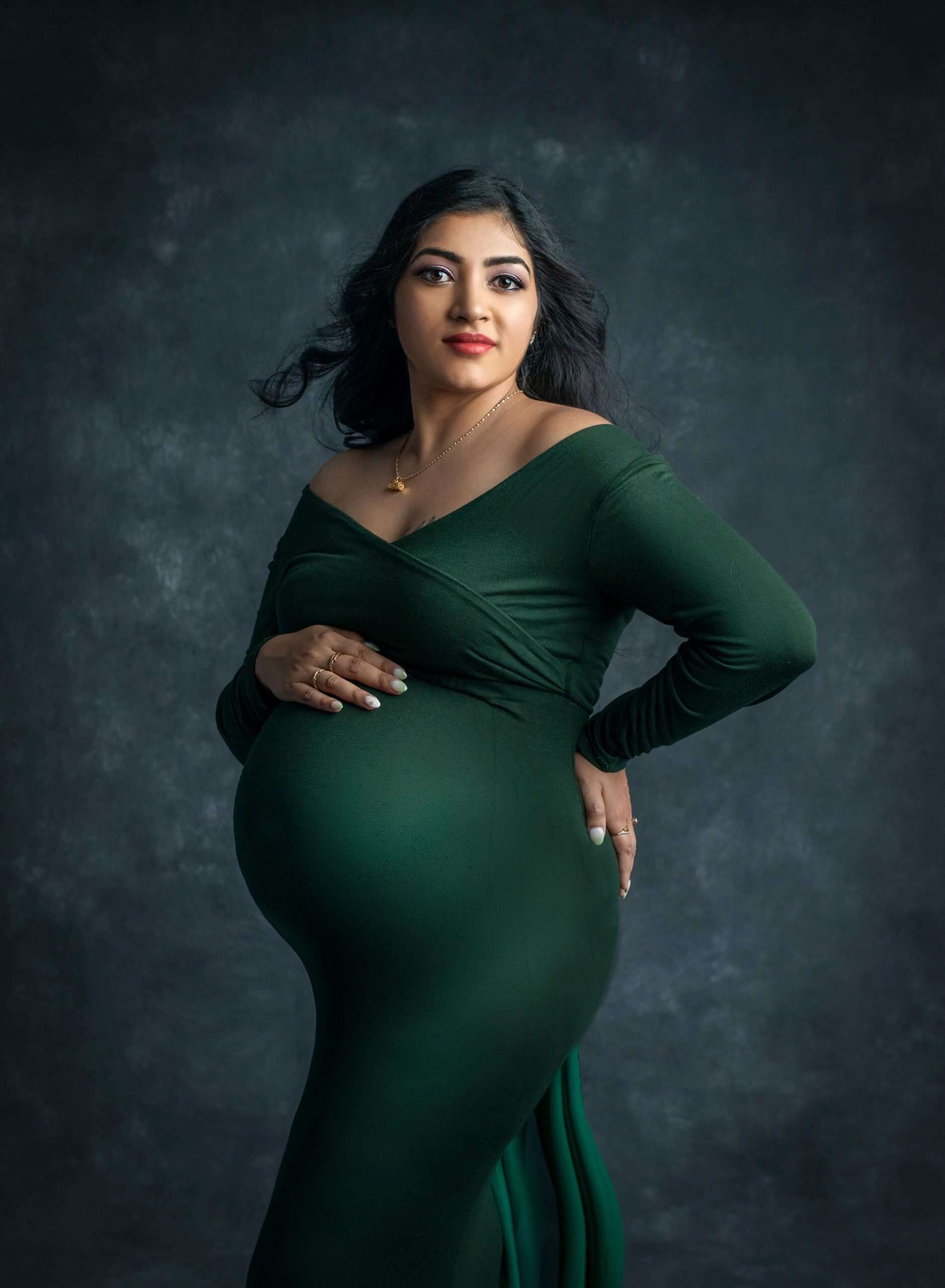 pregnant woman posing in green maternity dress