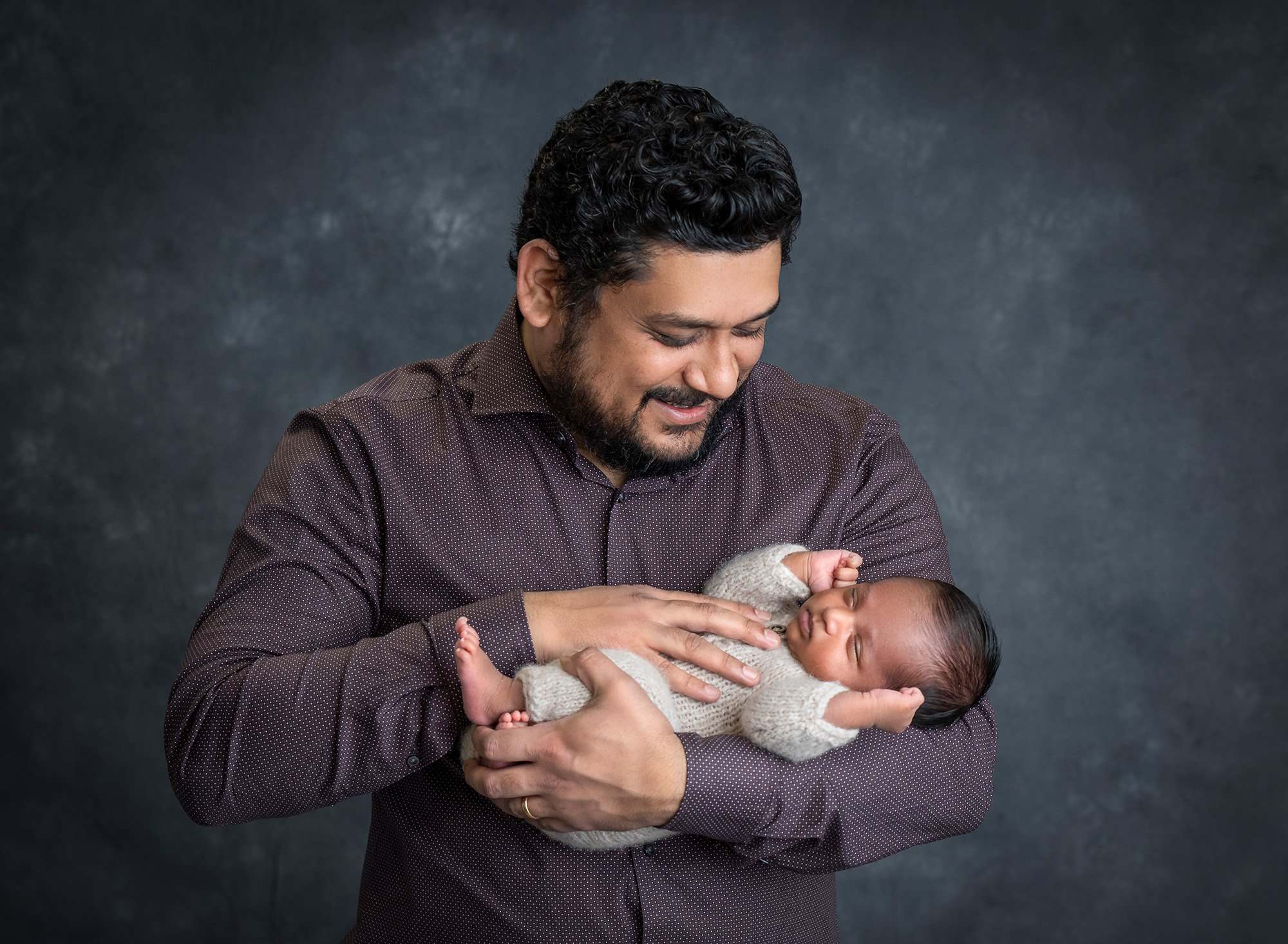 dad looking down on newborn son with hand on his stomach