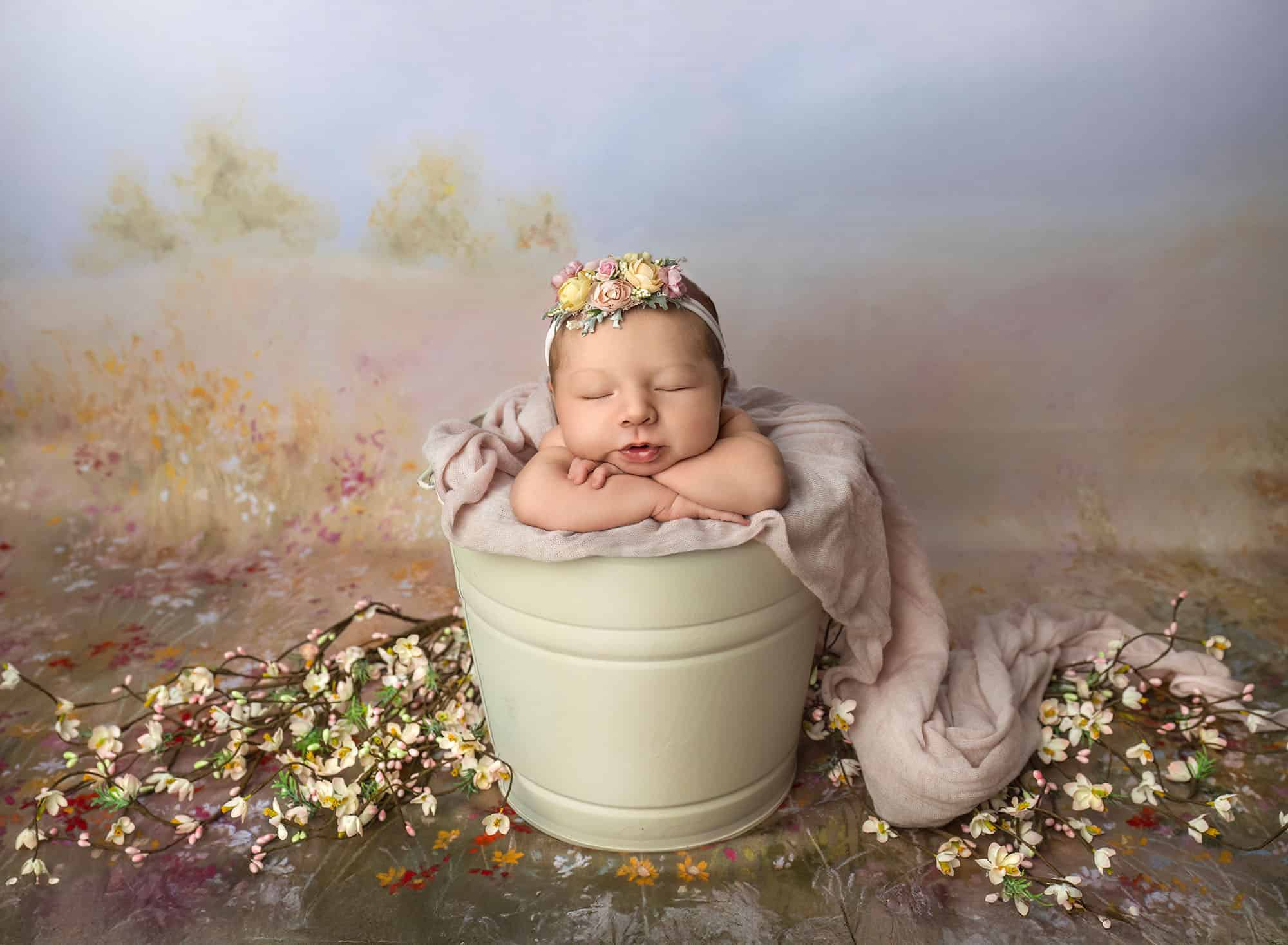 Newborn in bucket pose with floral crown—safe setup after preparing siblings for newborn photos