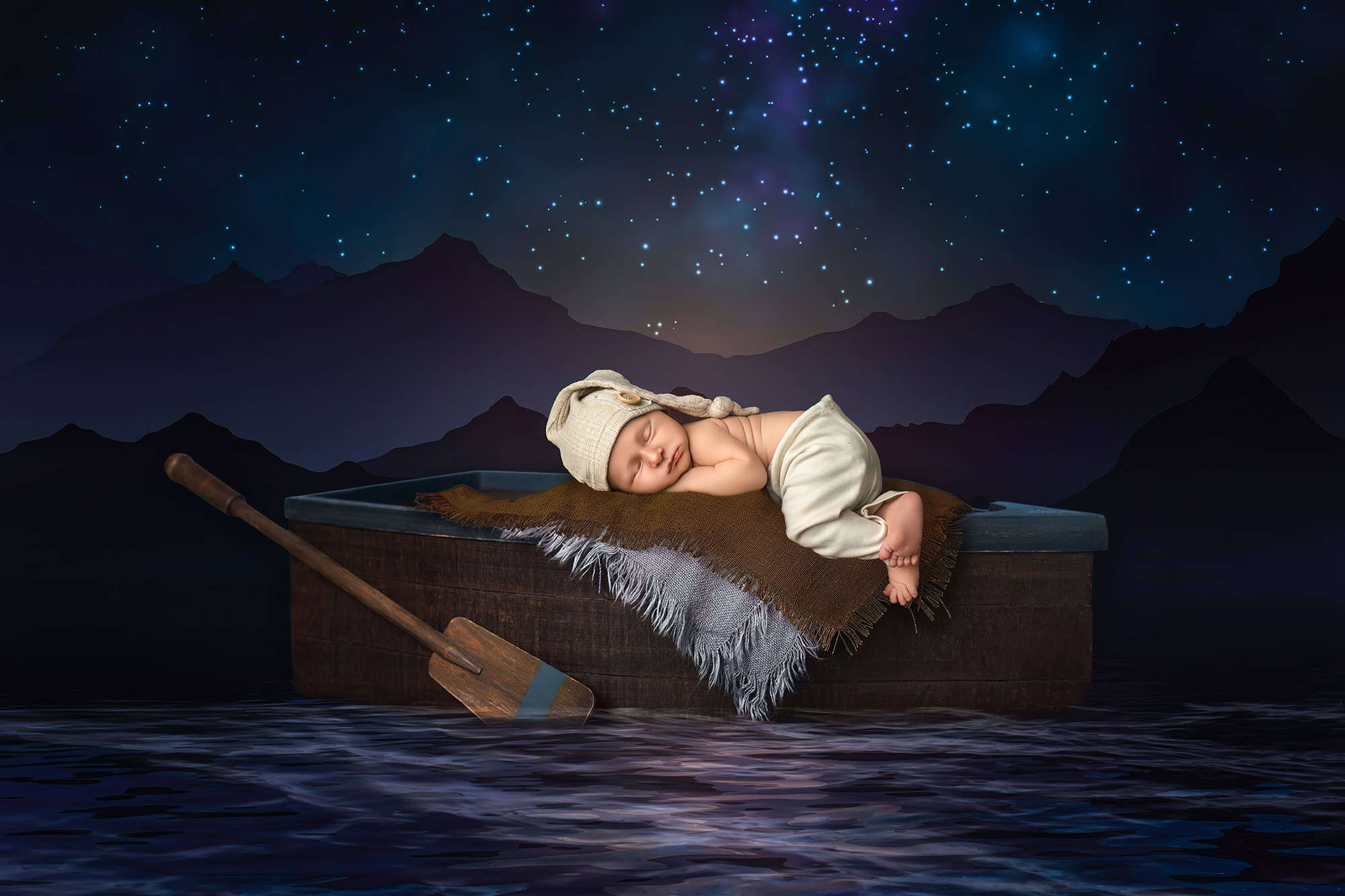 Creative baby photos Newborn Levi sleeping in a small boat under a starry sky backdrop.