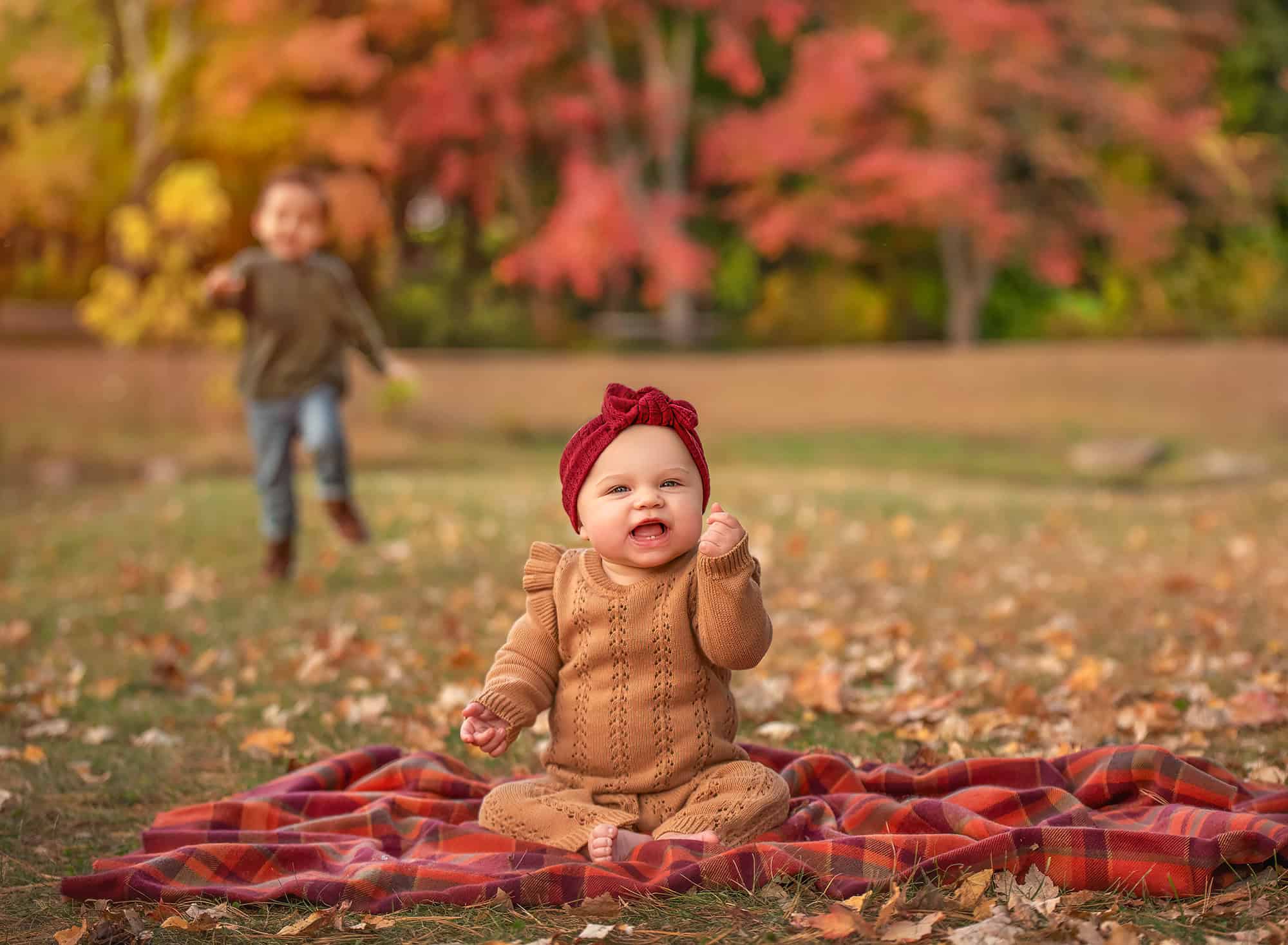 Kennedy laughing on the blanket while Lincoln runs in the background.