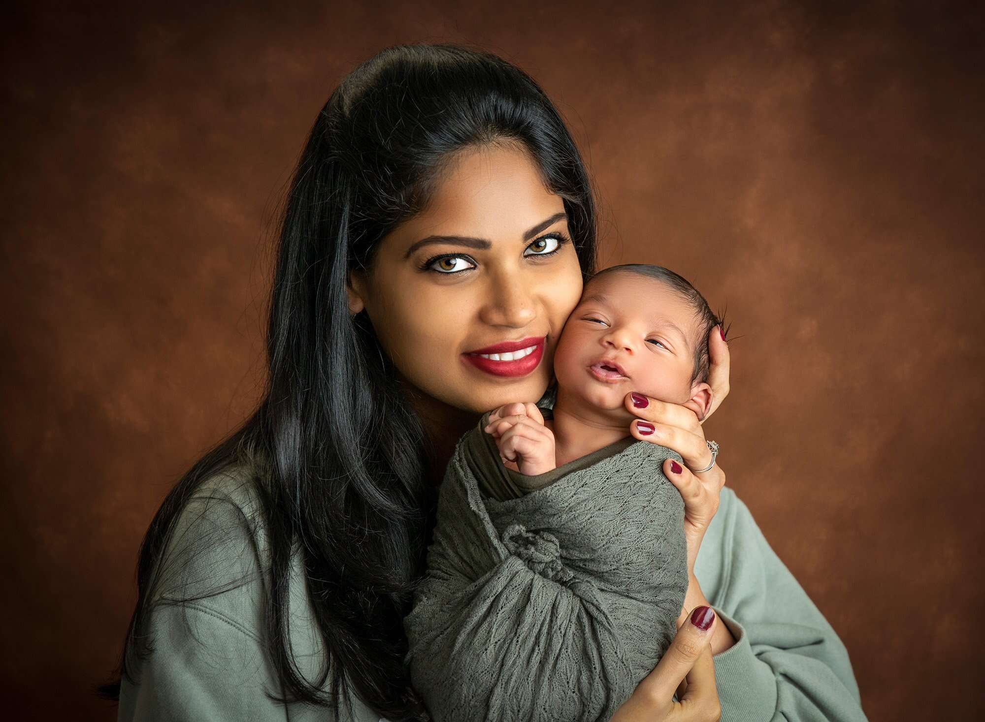 new mom snuggling newborn baby boy swaddled in green