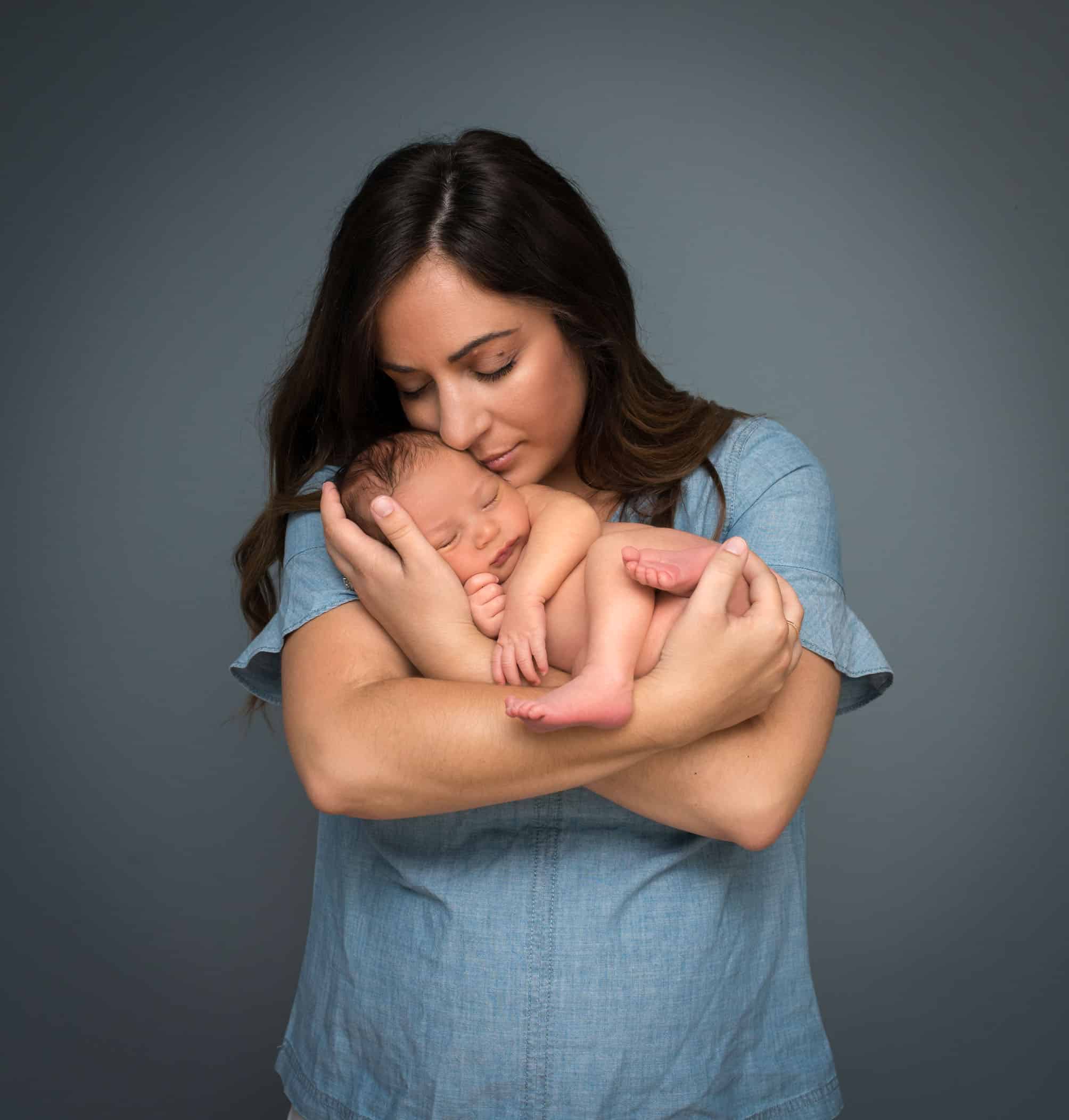 Mom cradling newborn in her arms and cuddling in
