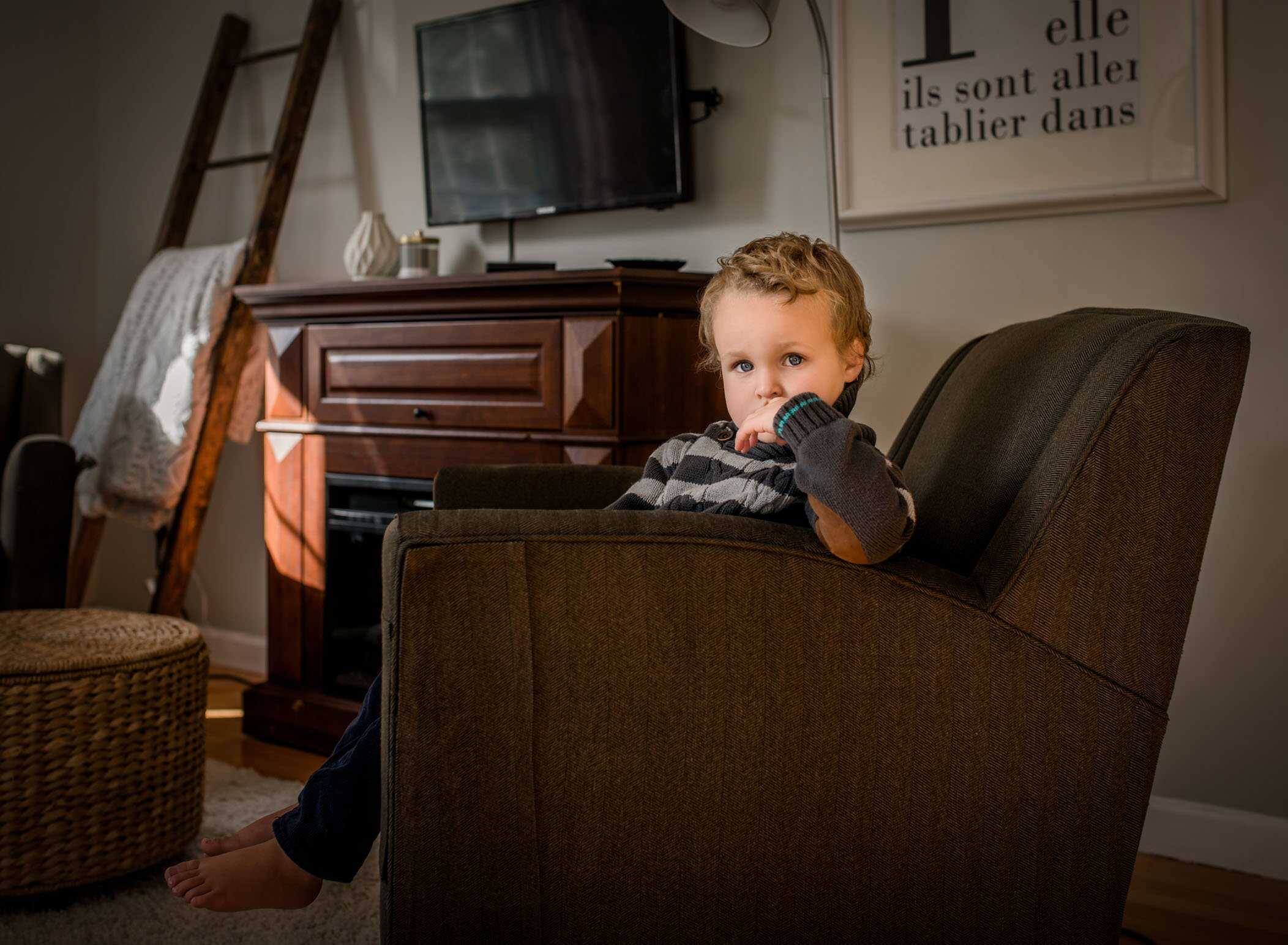 4 year old boy sitting in arm chair looking serious
