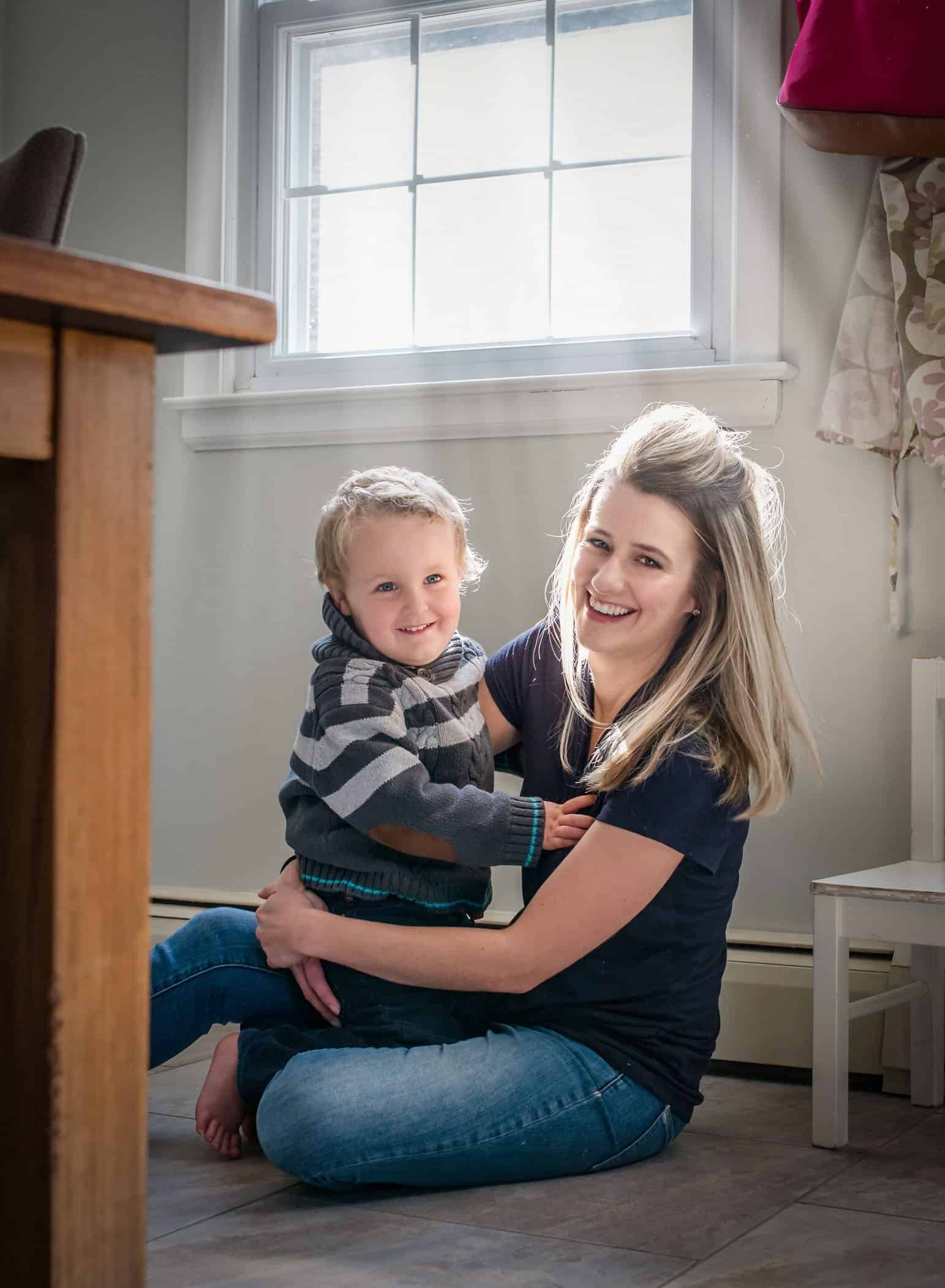 Mom and toddler son cuddling on kitchen floor
