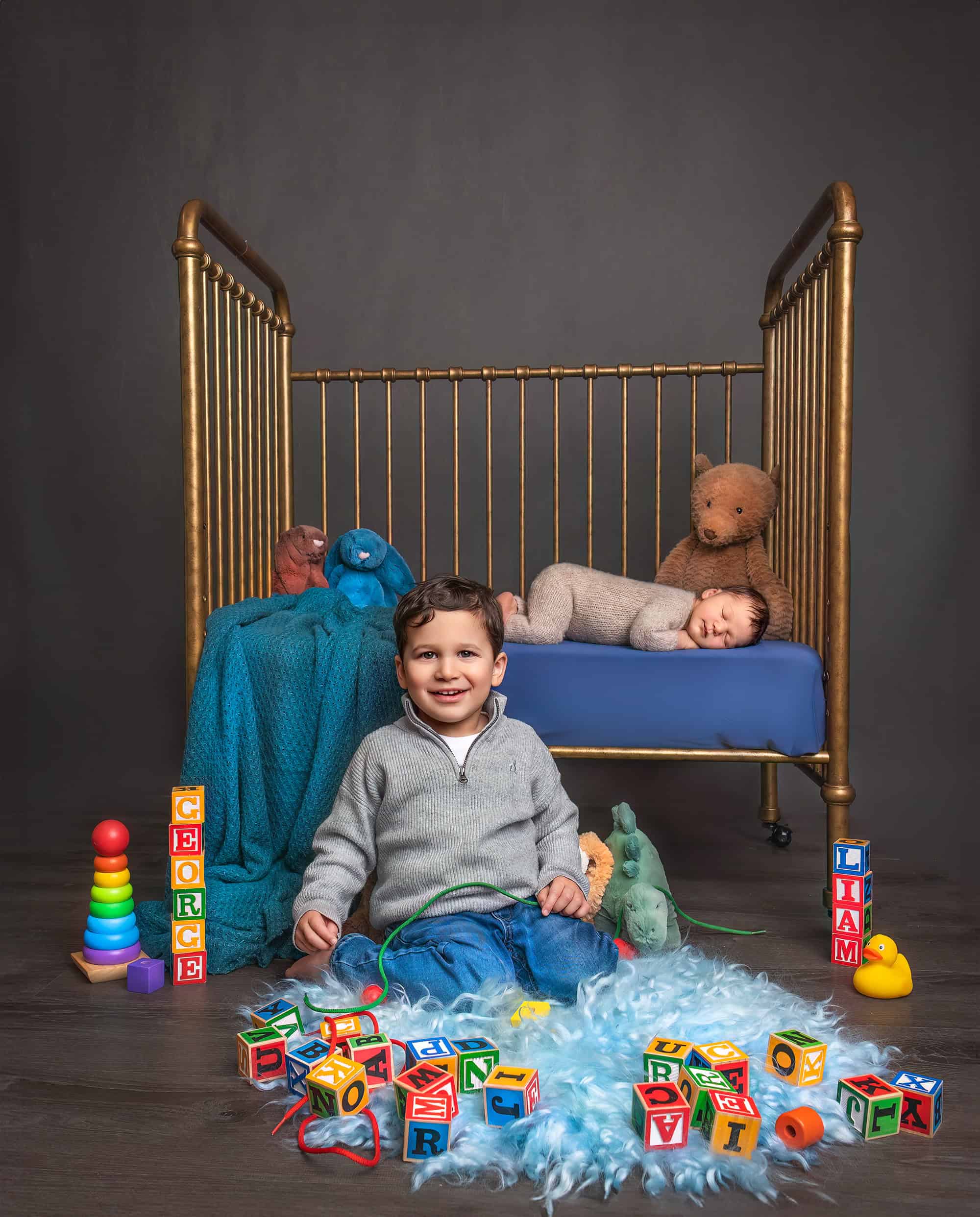 how to prepare for newborn photoshoot Glastonbury CT Newborn Family Photography Older brother playing with toys in front of crib newborn brother is sleeping in