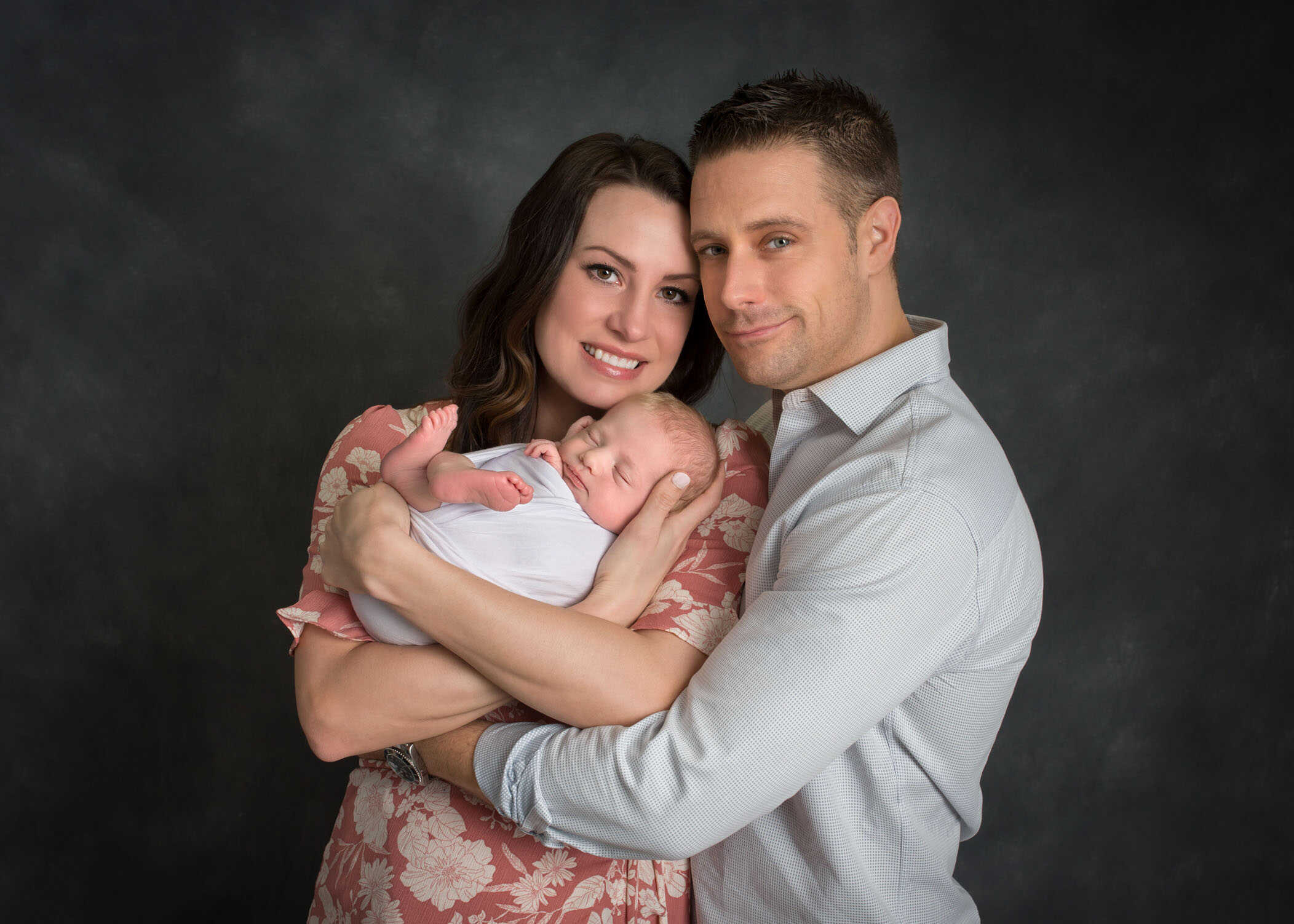 new Dad and Mom holding newborn son in their arms