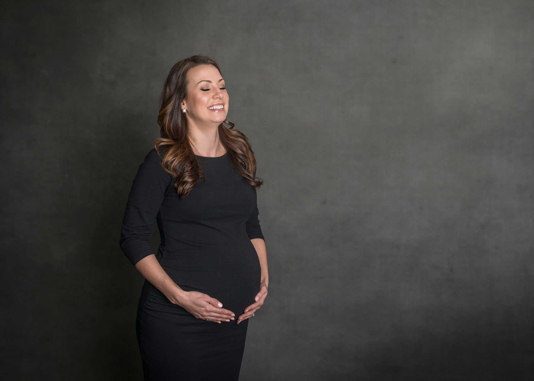 pregnant mom to be laughing while holding her belly