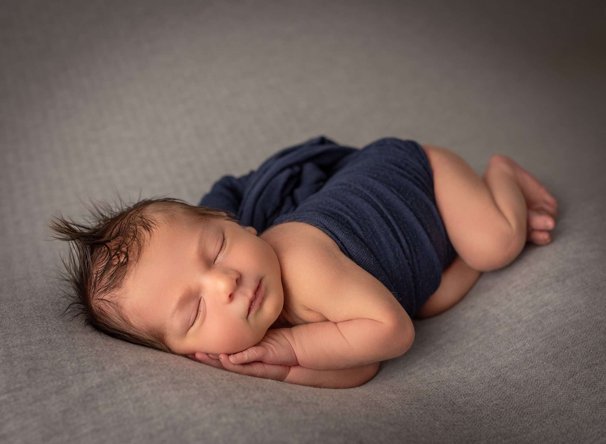 newborn baby boy asleep on his side wearing blue wrap