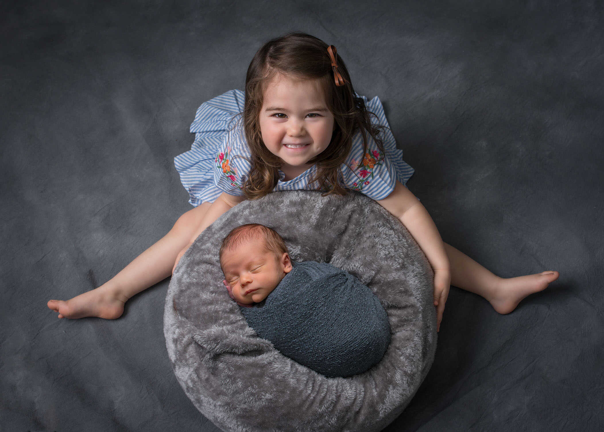 two year old sister smiles over her newborn baby brother