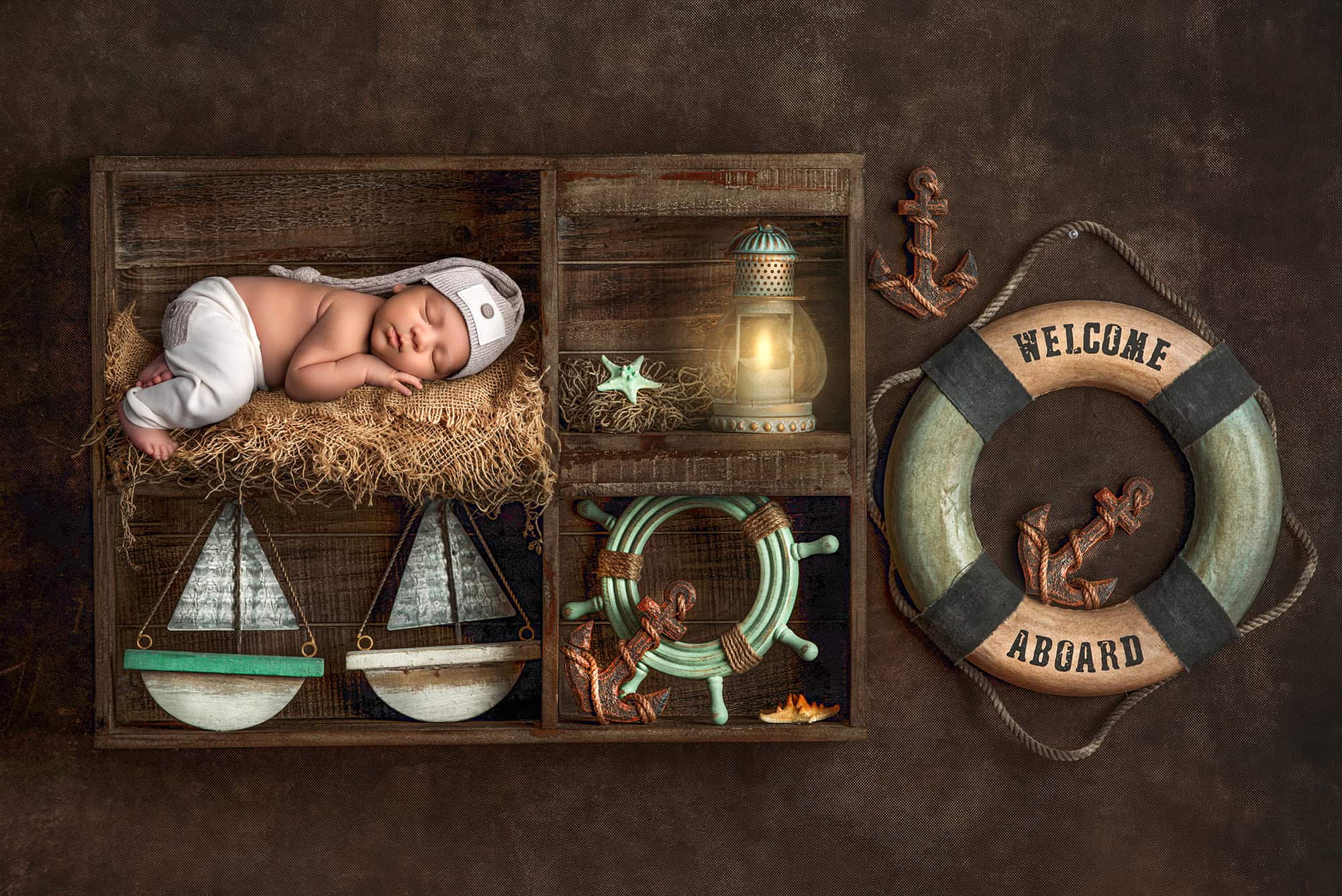 best newborn photographer what is the best time for newborn photoshoot newborn sleeping on crate with welcome aboard ring
