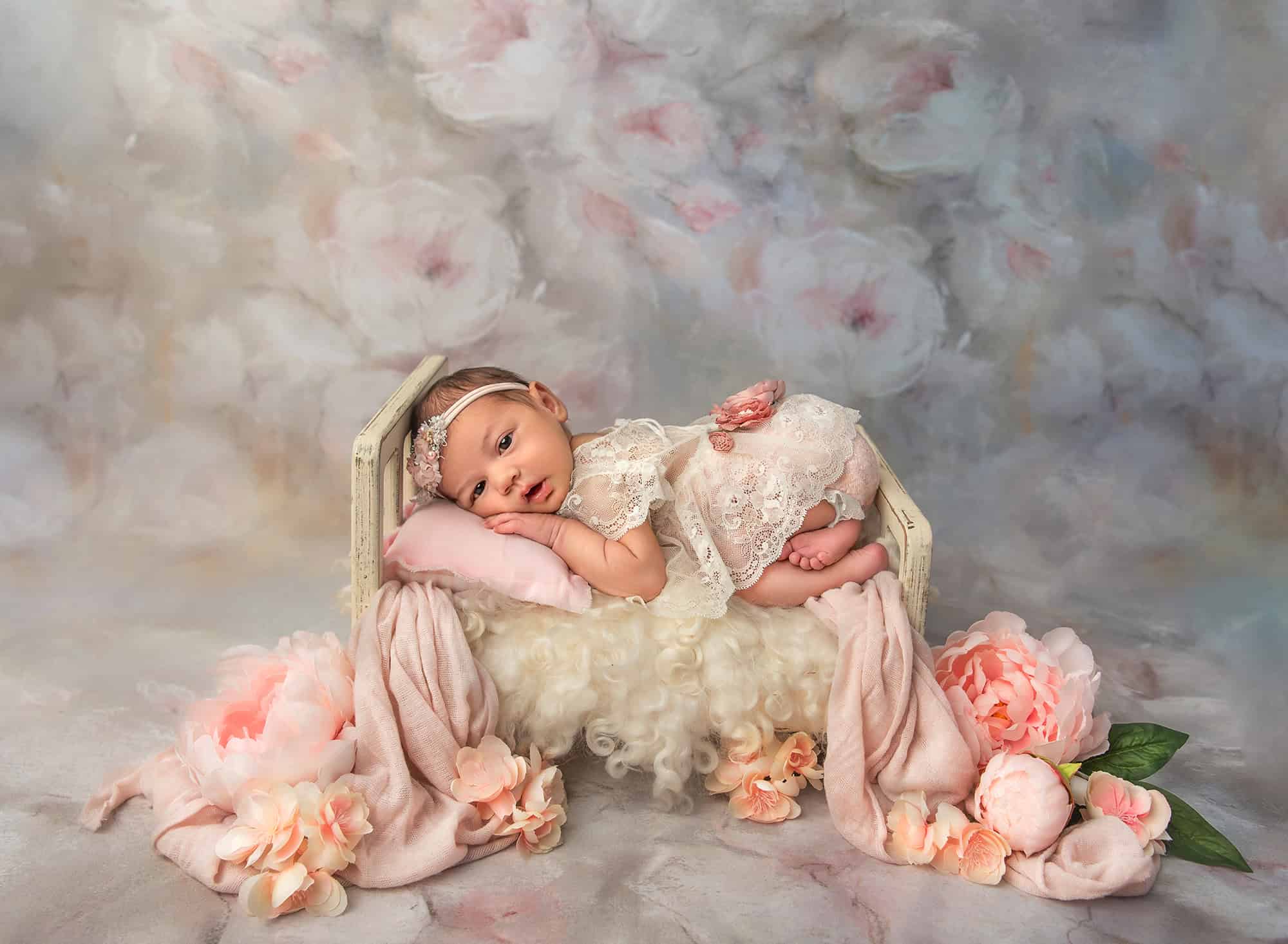 professional newborn photography baby girl laying on a painted bed surrounded by peonies on a peony background