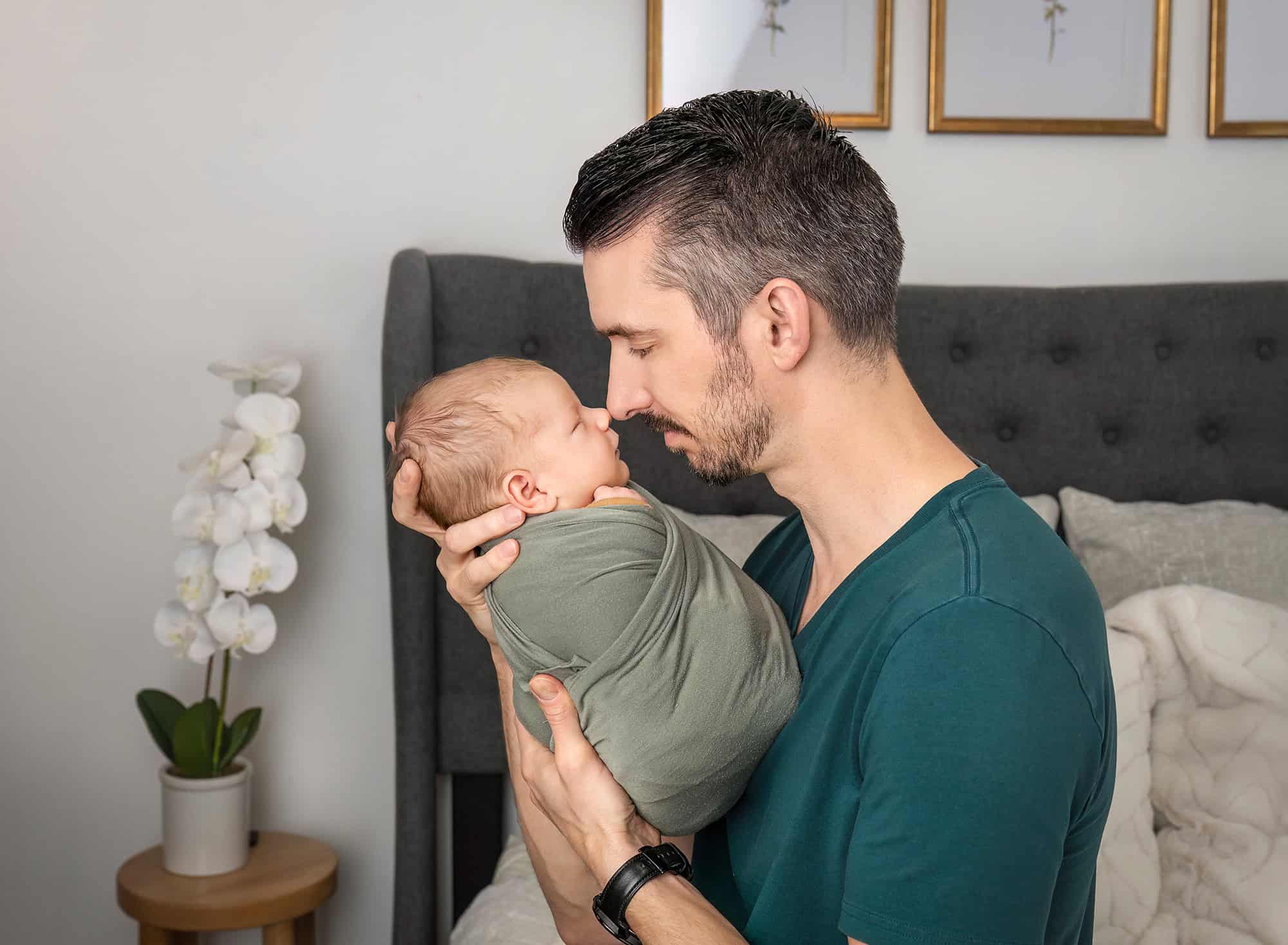 newborn photos with dogs—father and swaddled Leif touching noses in quiet moment