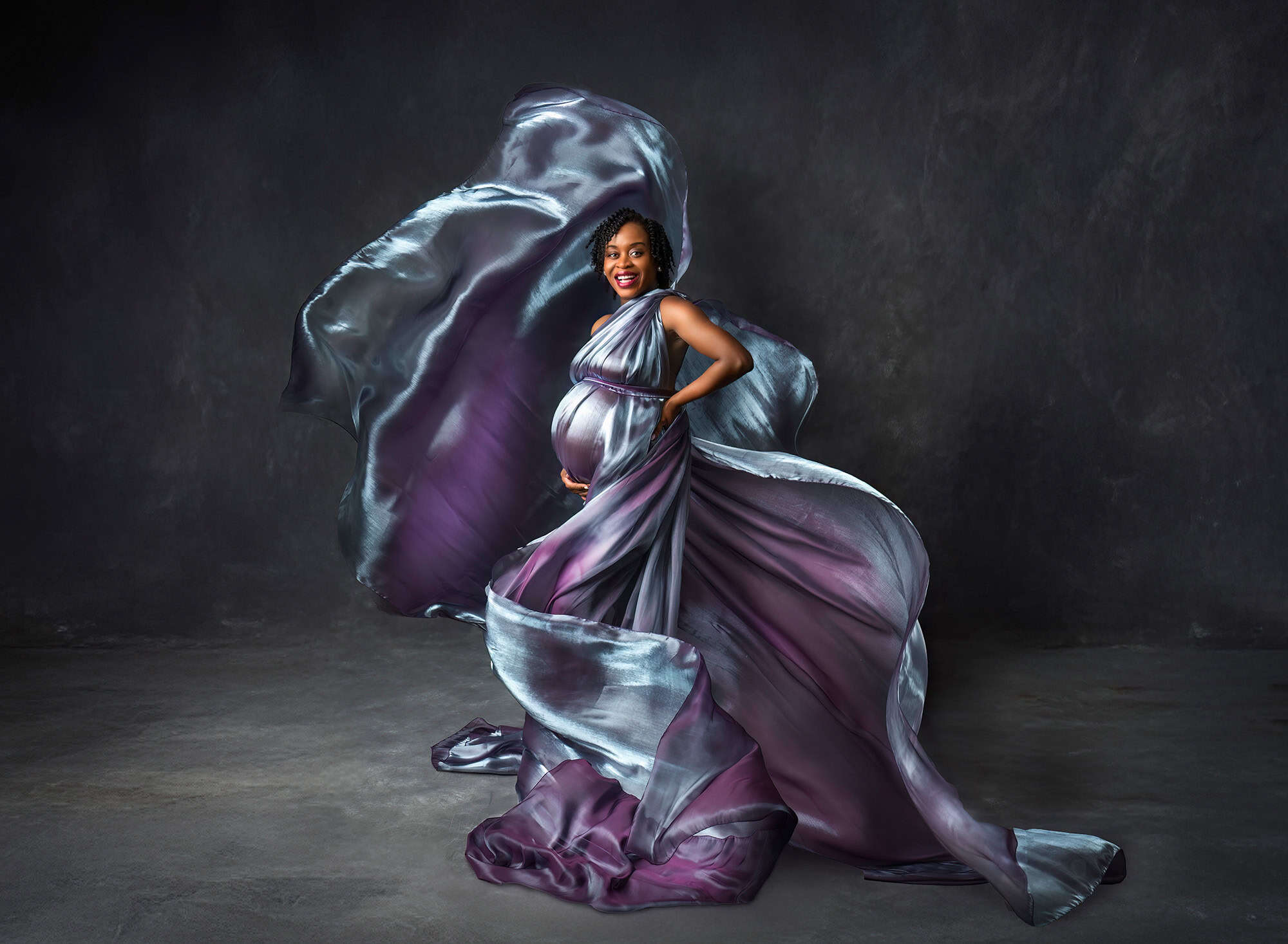 maternity and newborn photography pregnany woman with swirling blue and purple fabric around her and her baby bump