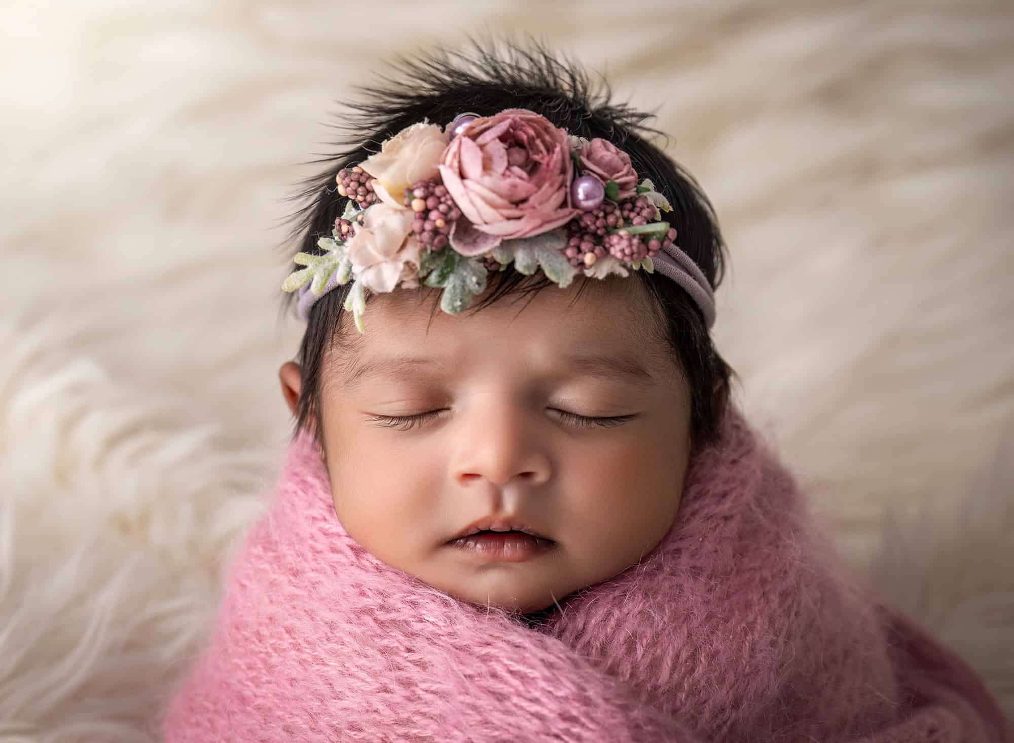 Luxury Newborn Photographer Glastonbury CT Close-up of newborn baby Anahita wrapped in mauve on a cream blanket
