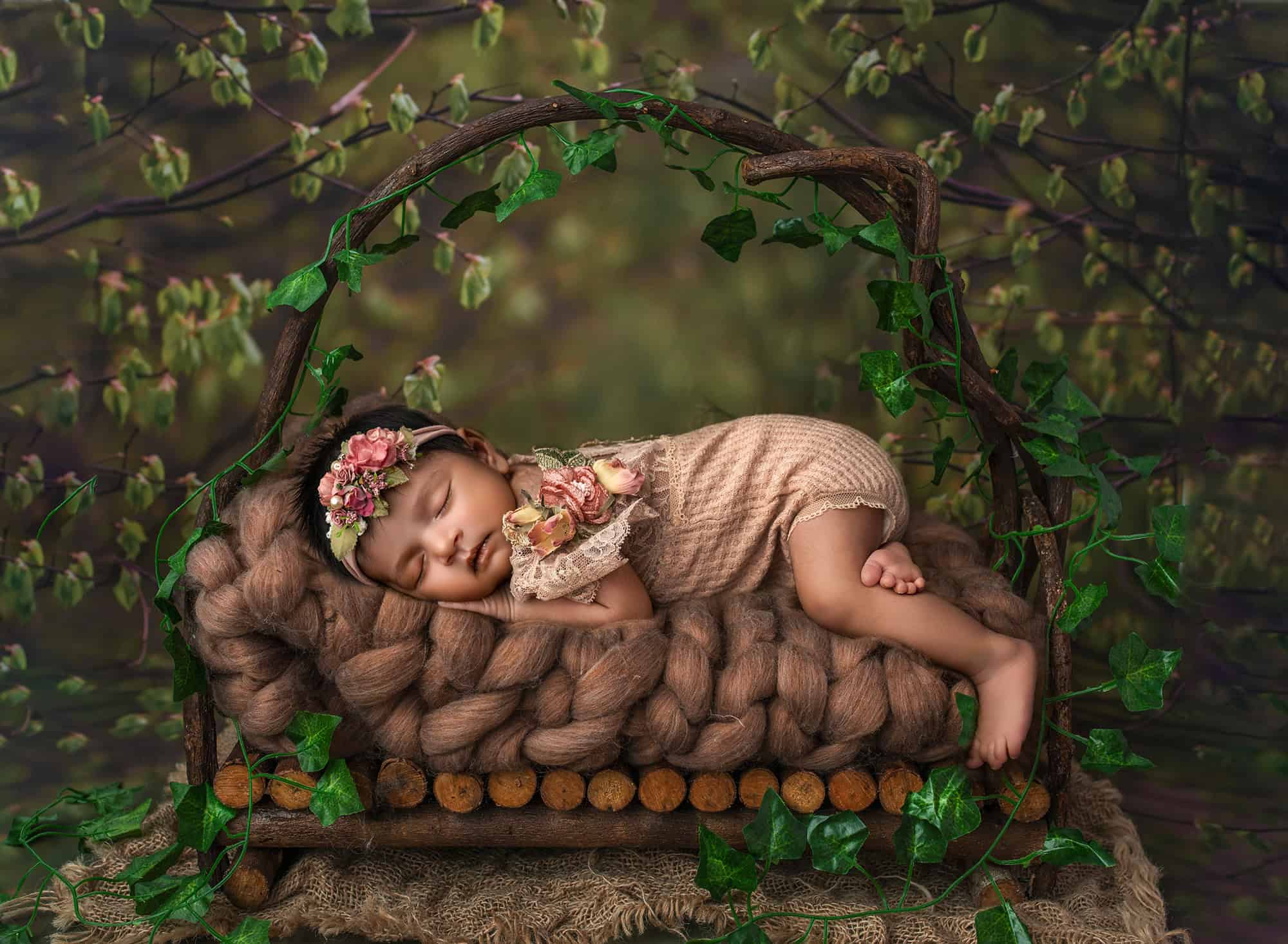 Luxury newborn photographer Glastonbury CT Sleeping Anahita on a rustic bed in a forest scene with green vines