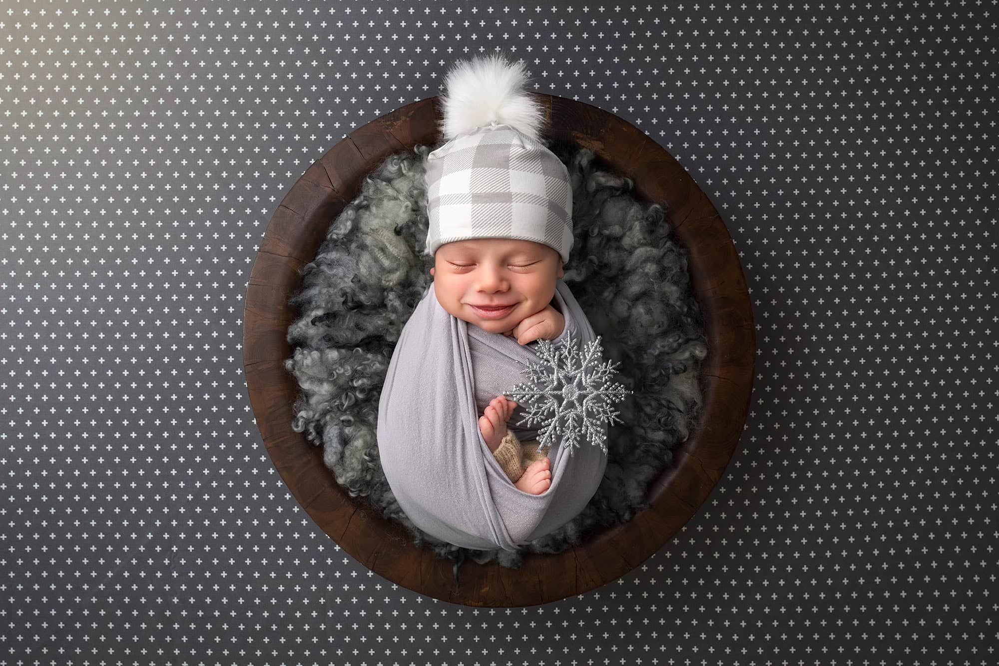 High-End Newborn Photography Connecticut smiling newborn boy holding a silver snowflake