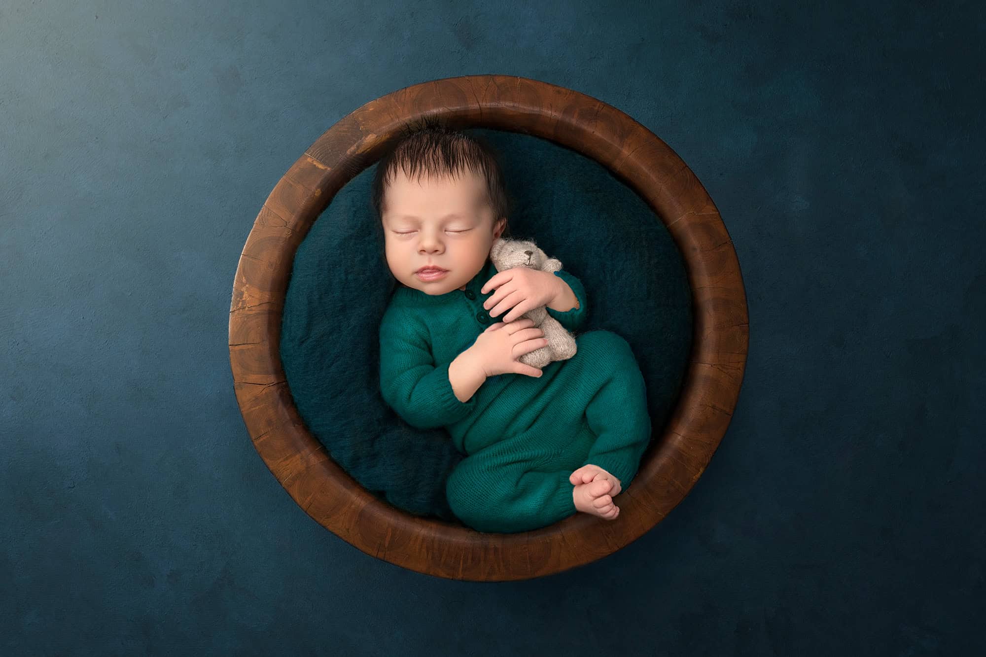 High-End Newborn Photography Connecticut tiny newborn boy holding a tiny teddy bear in a wooden bowl