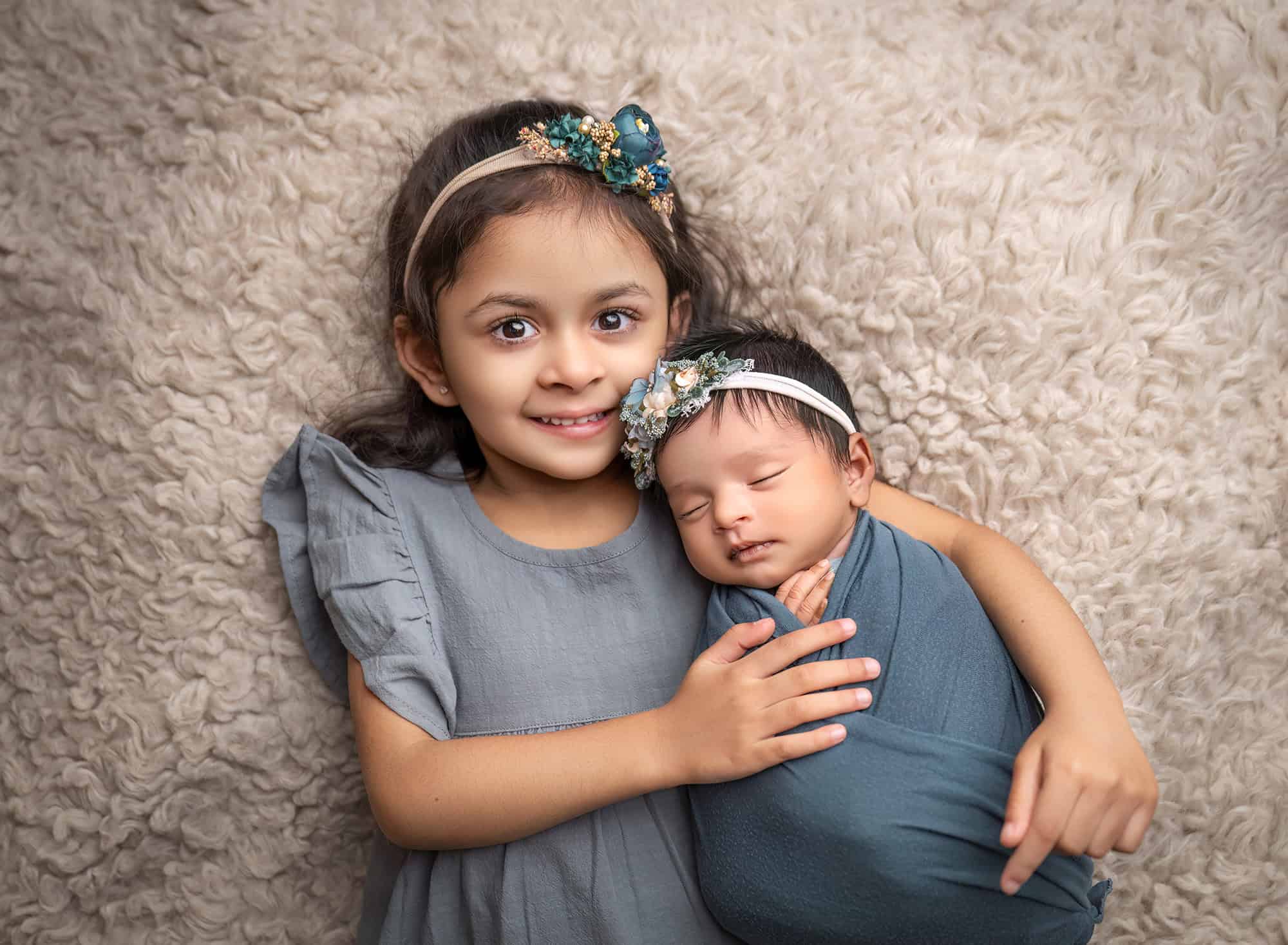 Big sister Aarya snuggling newborn Anahita