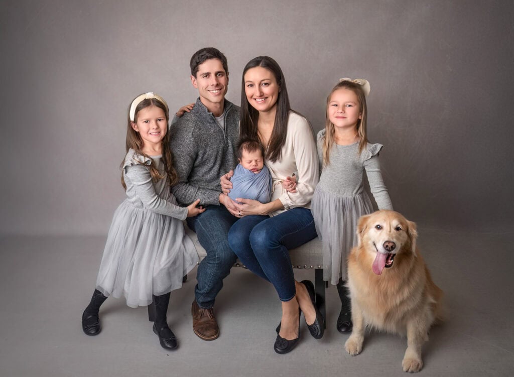 High-end newborn photography ConnecticutFamily portrait with parents, two daughters, and a golden retriever, with newborn baby Max