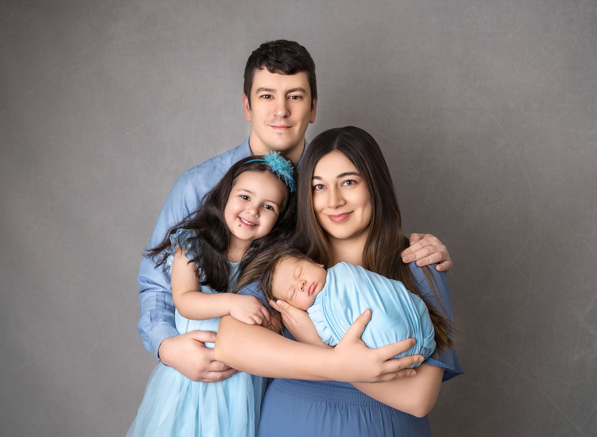 Family portrait in soft blue. Big sister and new baby brother with parents.