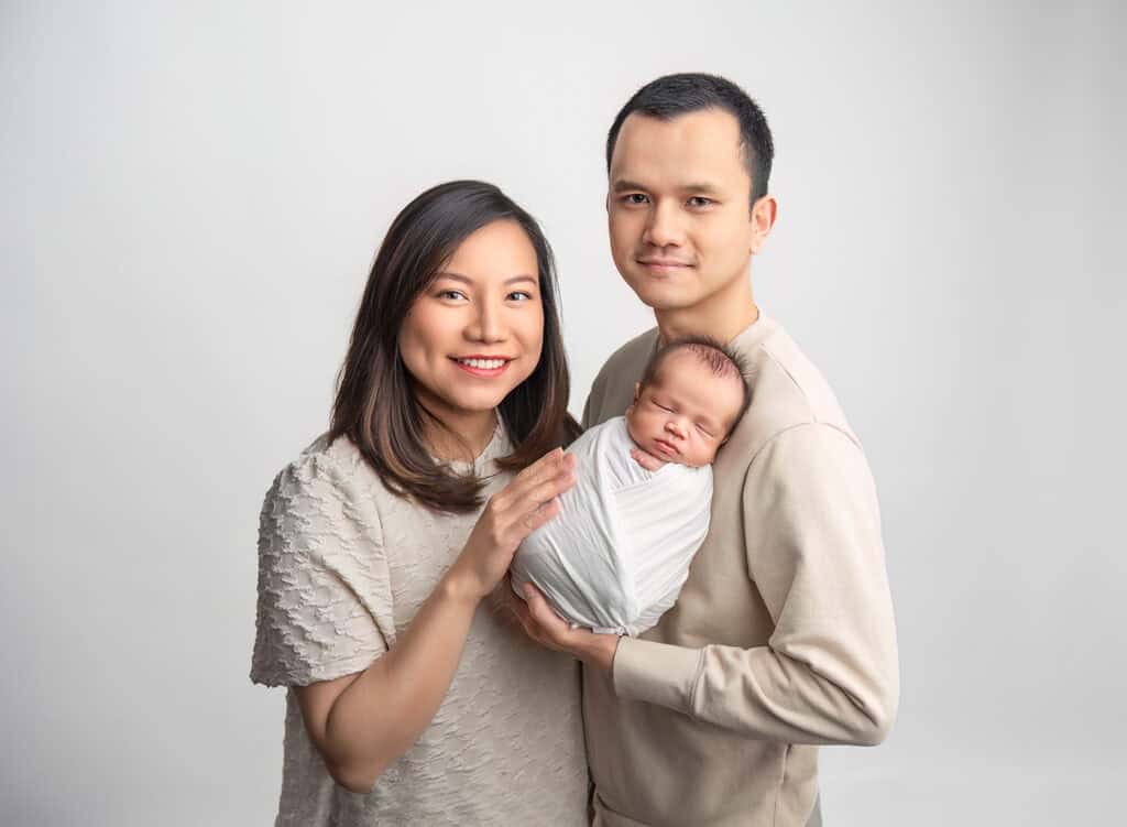 newborn photos what to wear parents of newborn baby with baby sleeping on dad's shoulder and mom with her hand on the baby