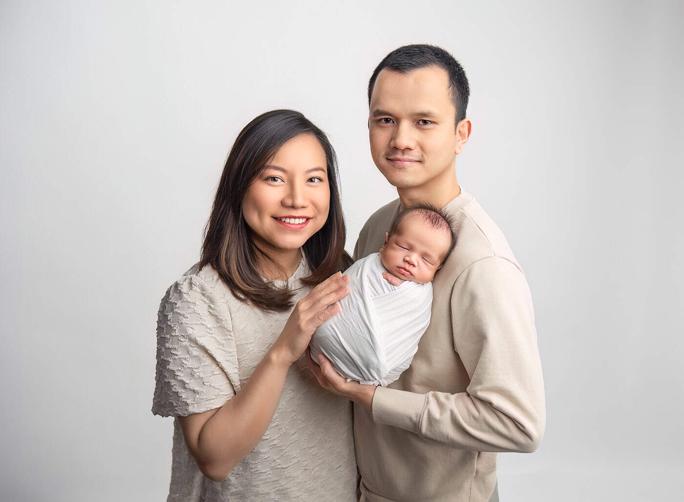 parents of newborn baby with baby sleeping on dad's shoulder and mom with her hand on the baby