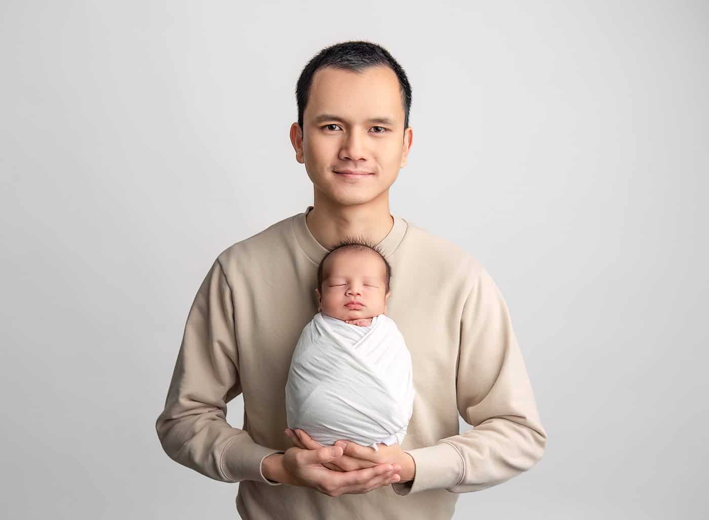 dad of newborn baby holding baby in the center of his chest