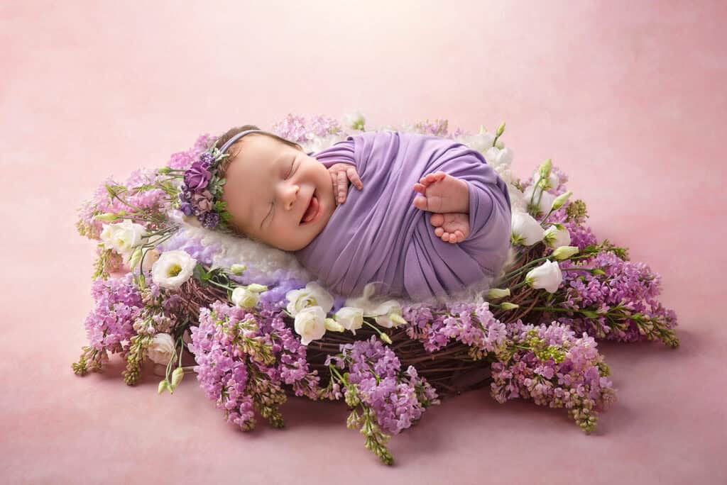 best newborn photographer CT newborn photographer baby smiling in a nest of lilacs