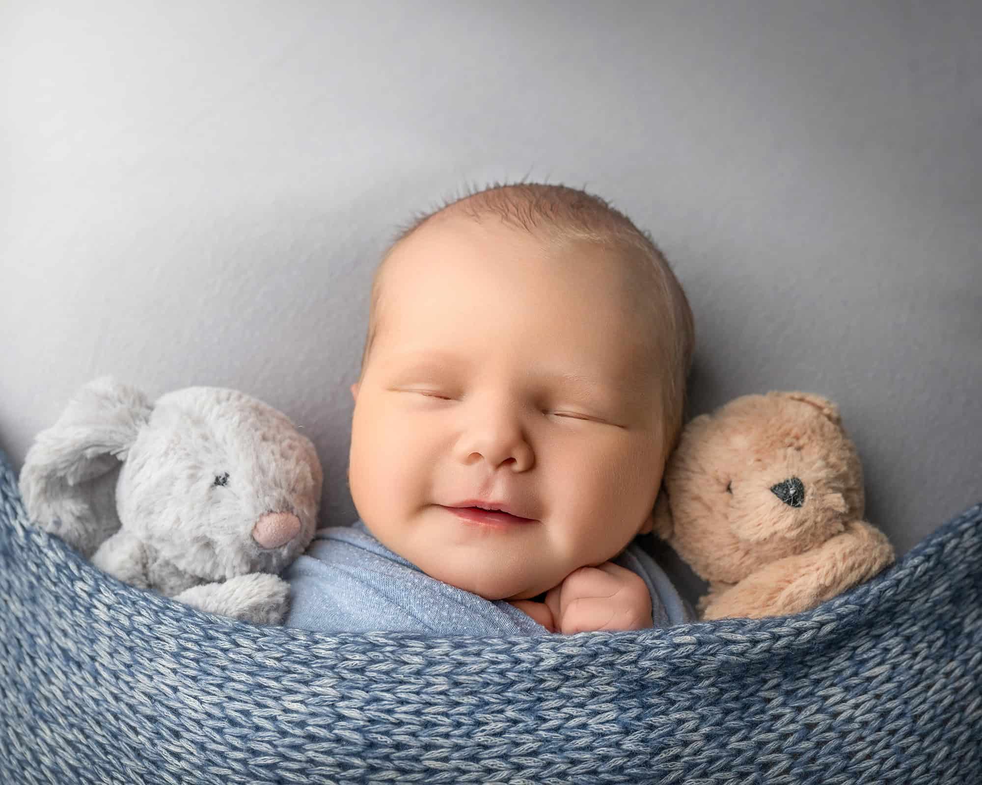 Baby in nighty-night pose with stuffed animals in Glastonbury CT newborn photography studio.