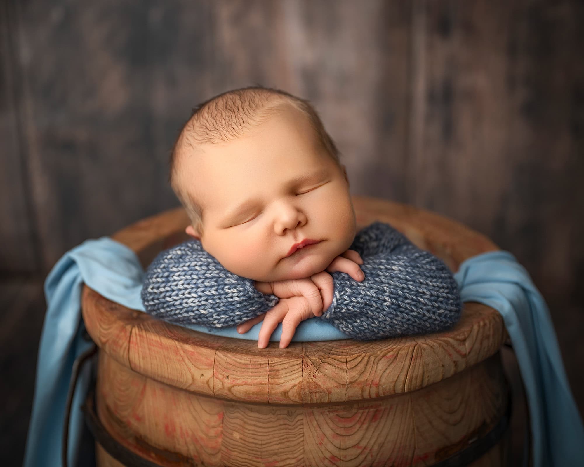 Glastonbury CT newborn photography studio Baby boy asleep in heads-on-hands pose in honey wooden bucket