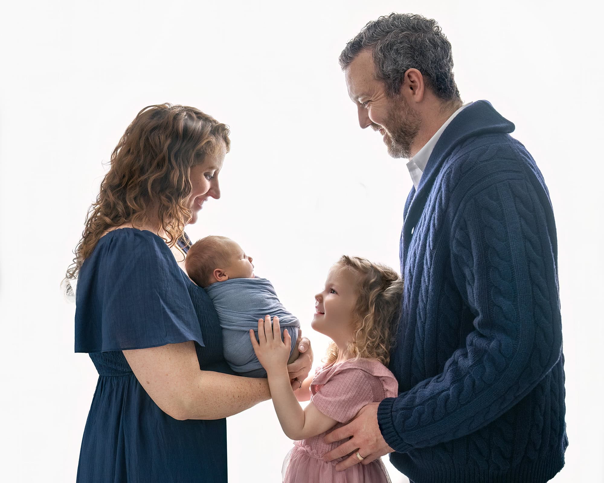 Parents smiling down at newborn during professional newborn session in Glastonbury CT.
