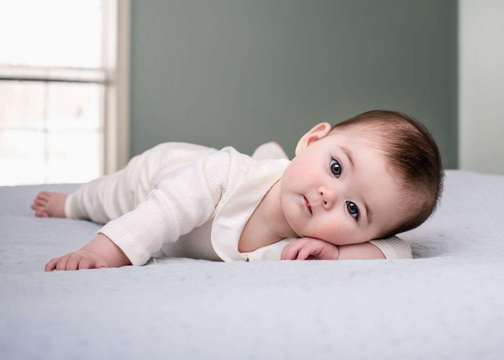 6 month old baby resting on her tummy with her arm under her head
