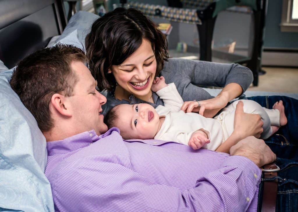 Daddy, Mommy and 6 month old baby cuddled on the parents bed for some tickle time