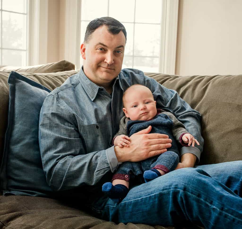 3 month old baby boy sitting with Daddy on the couch