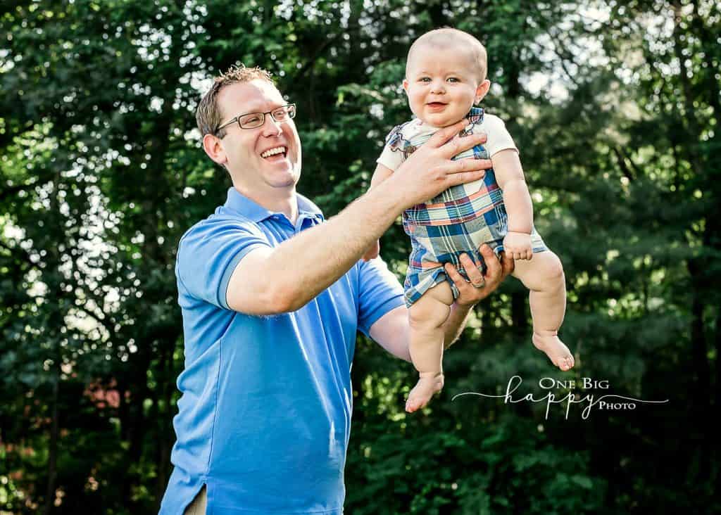 Daddy flying 6 month old son around the yard in summer