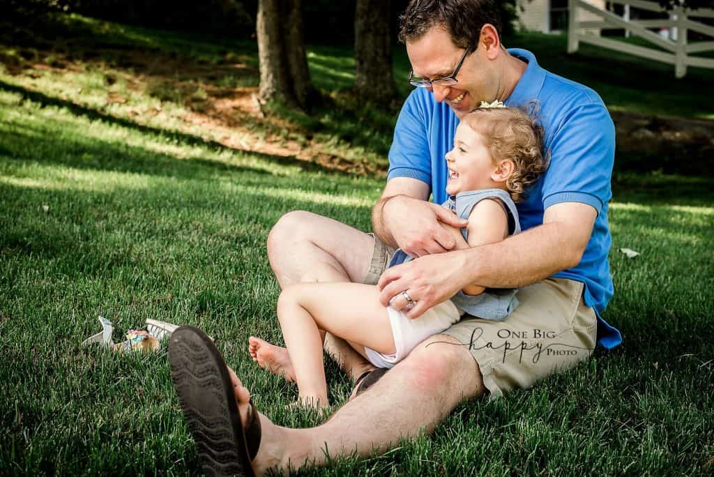 Daddy tickles young daughter in the grass