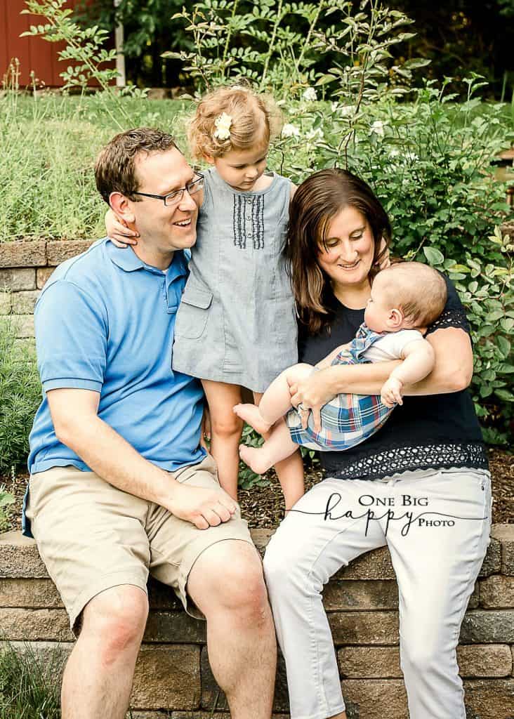 Family of 4 sitting on a brick wall outside in summertime
