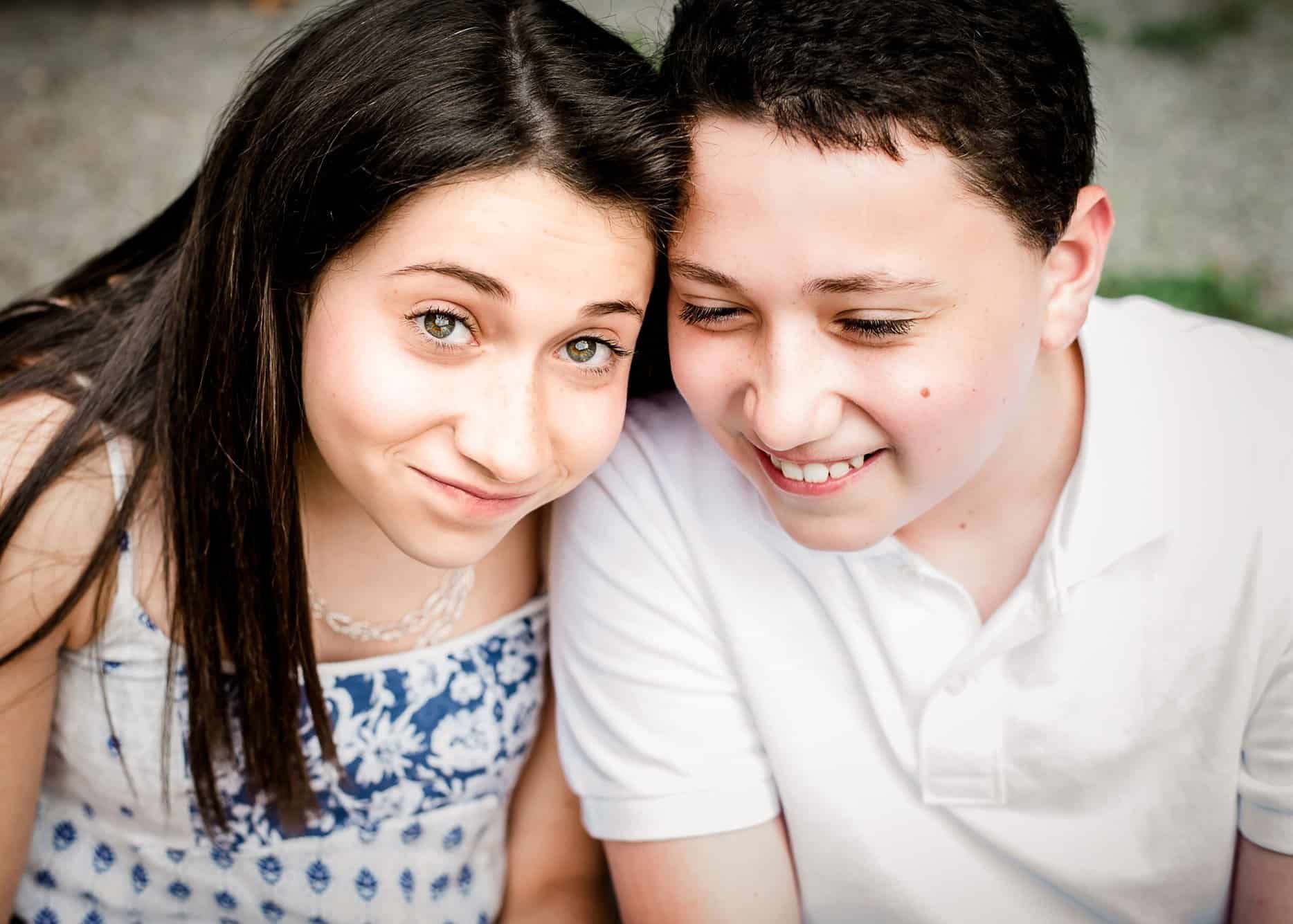 brother and teen sister laughing with heads together