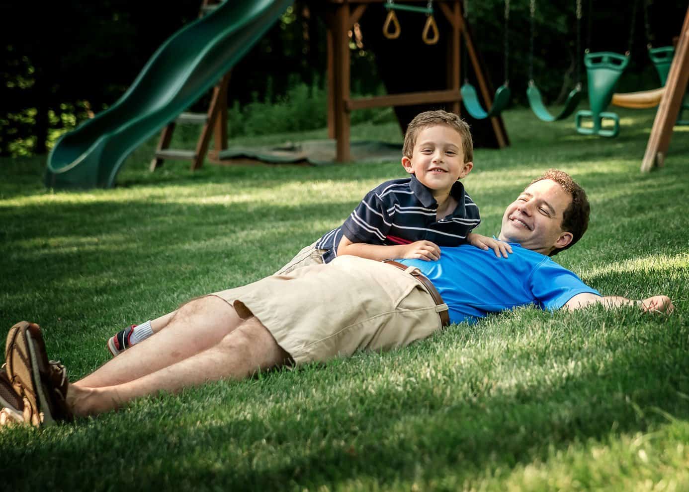 Dad and young son lying in the grass playing