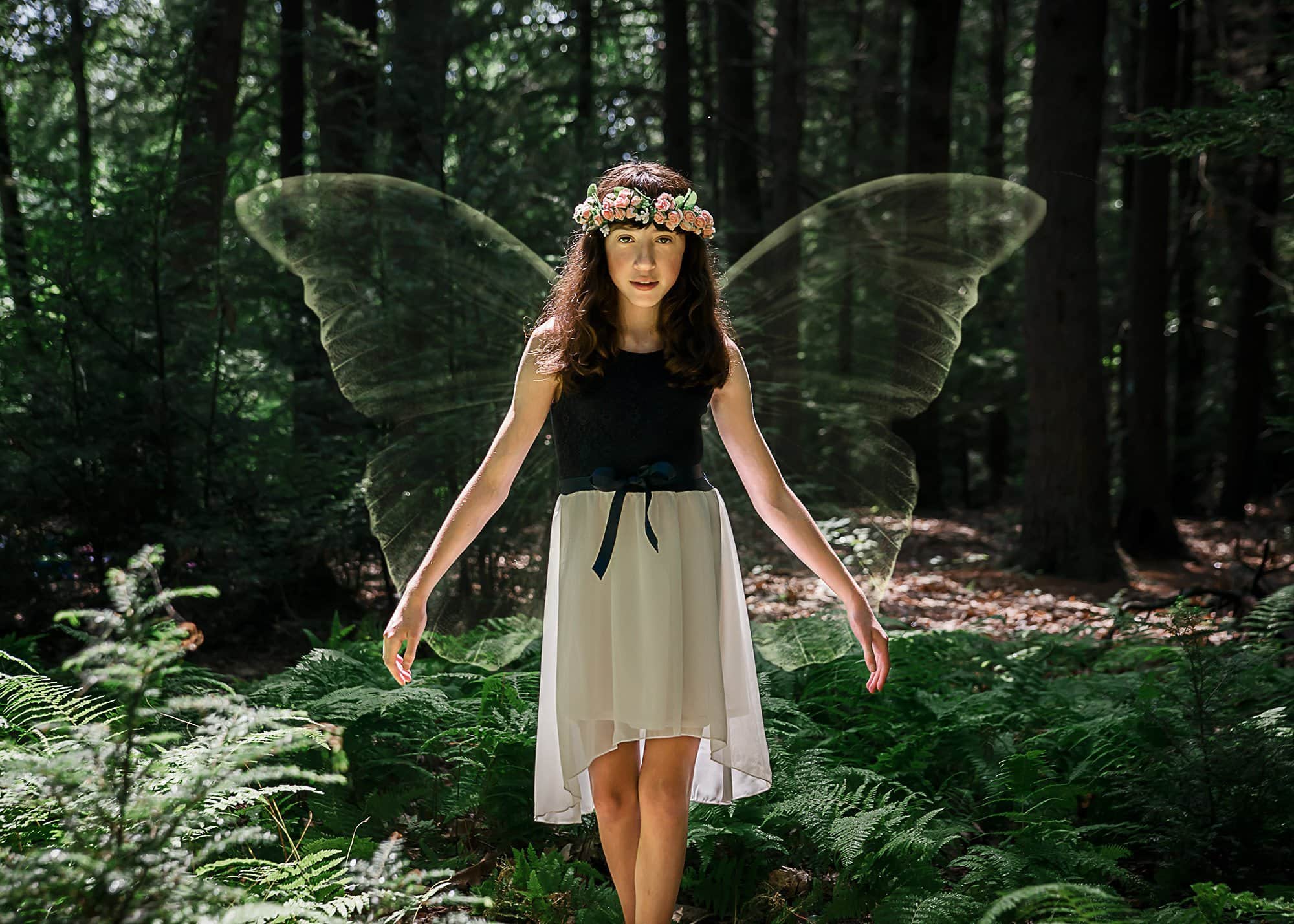 little girl with a floral crown and fairy wings in the forest