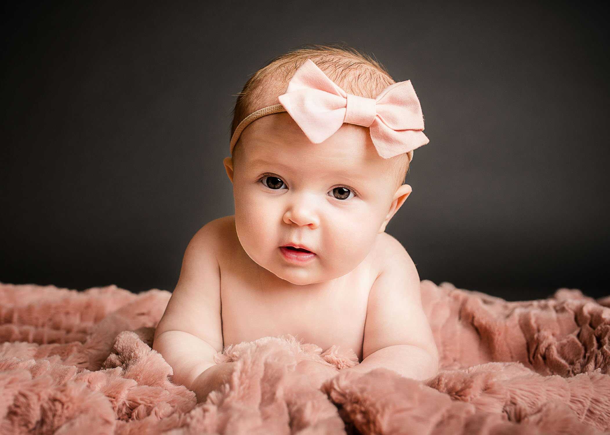 baby girl with pink bow lying on pink furry blanket One Big Happy Photo