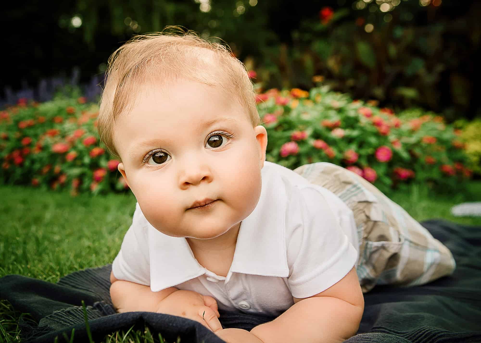 6 month old little boy playing outside on his tummy in the garden