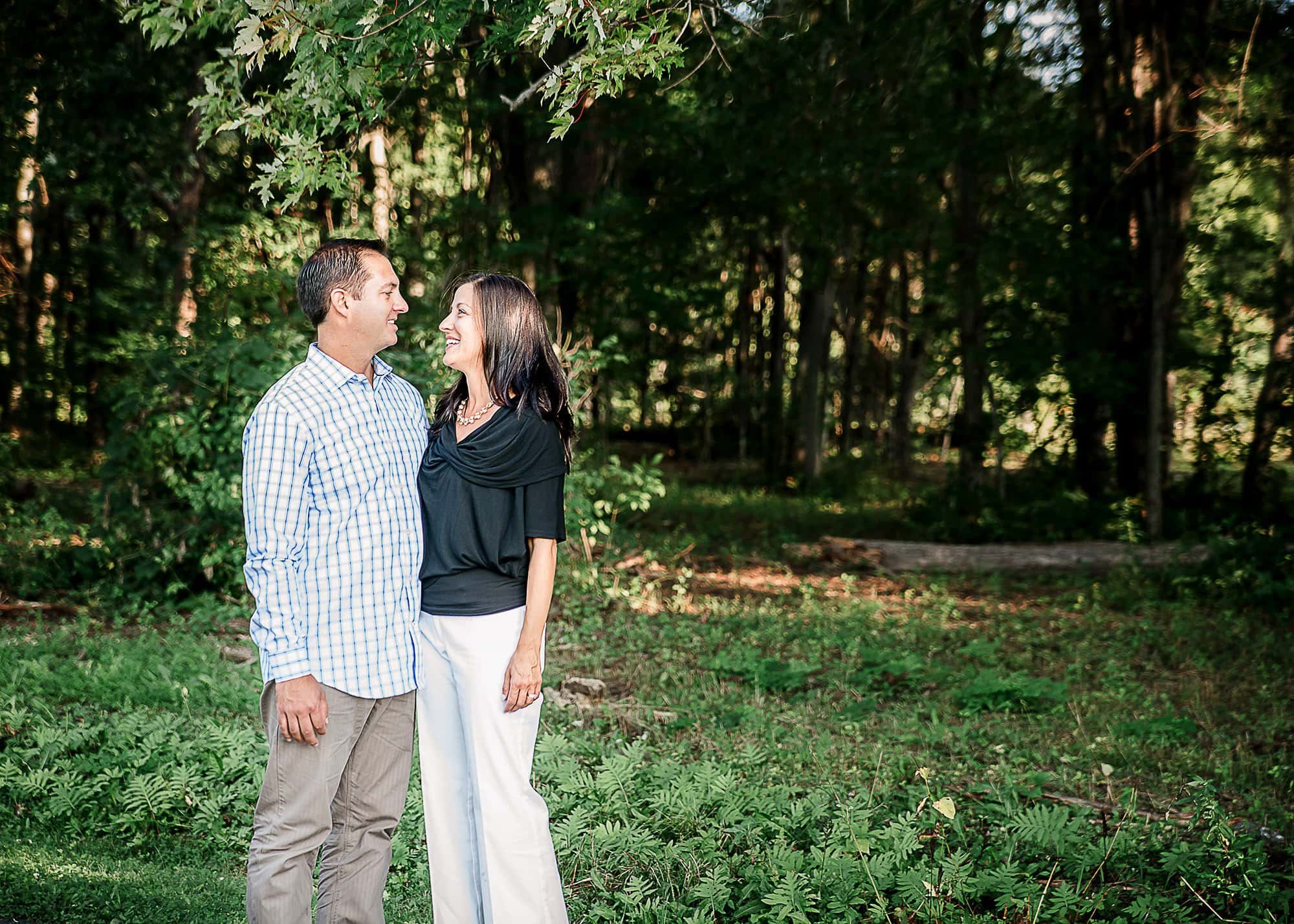 Couple standing outside in summer talking with garden in the background