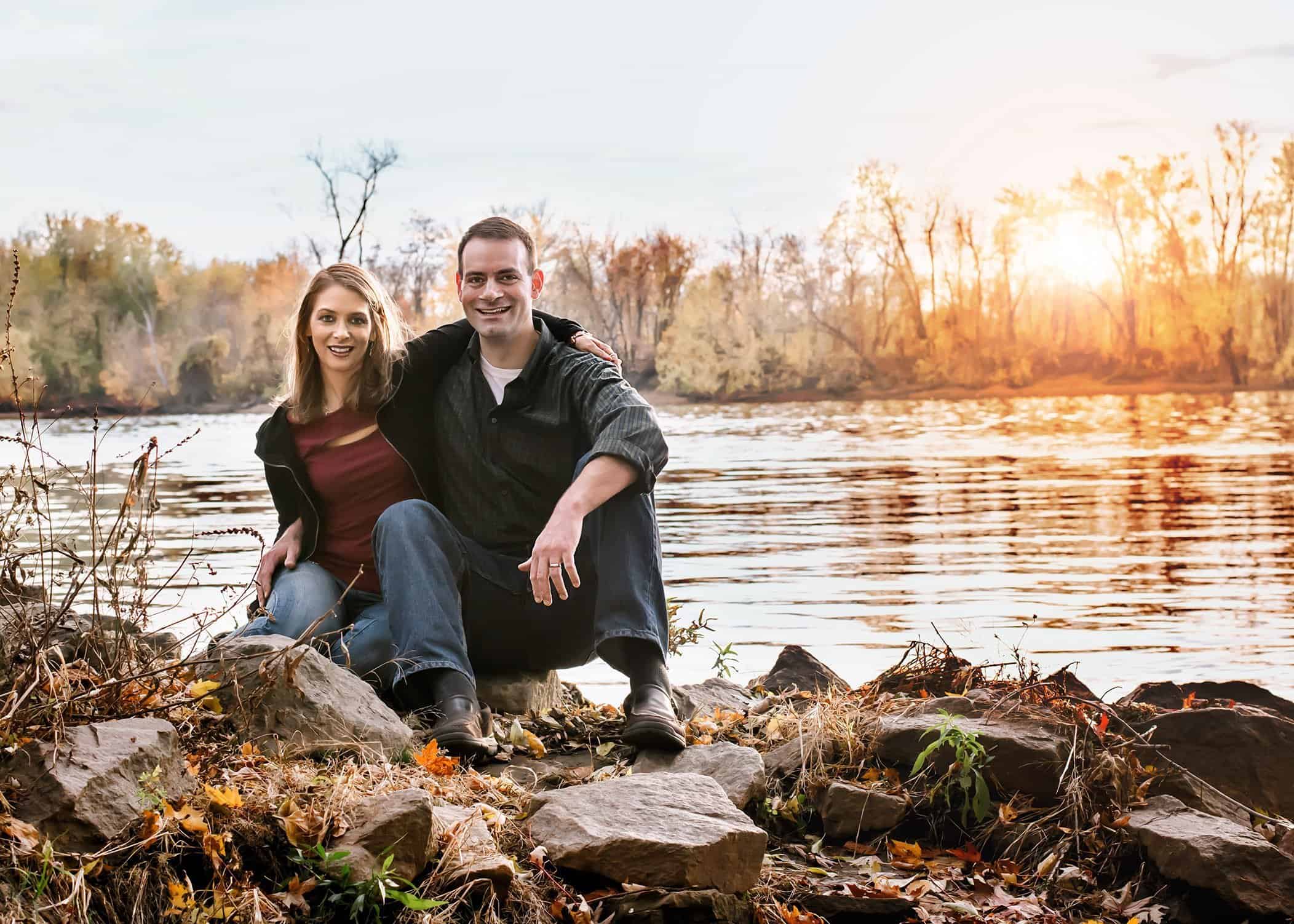 Mom and Dad sitting by the river at sunset in fall