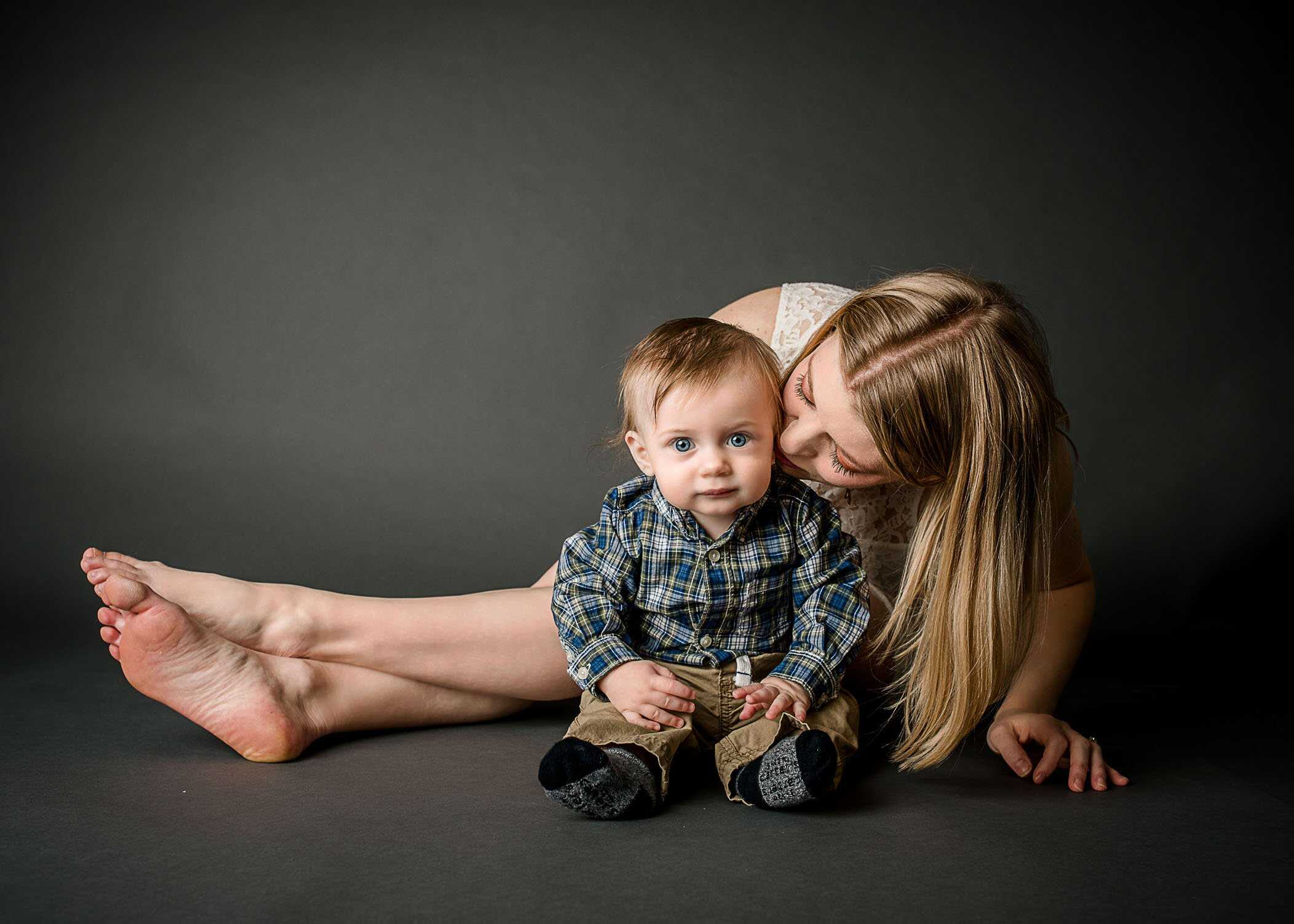 Mom leaning over to kiss baby boy on cheek
