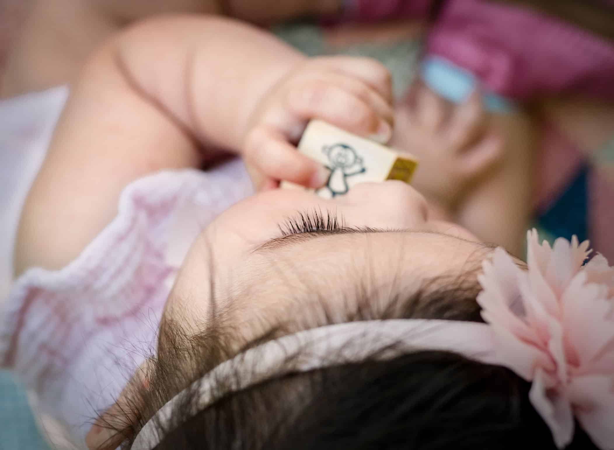 up close detail photo of 6 month old baby girl's eyelashes as she chews on a block