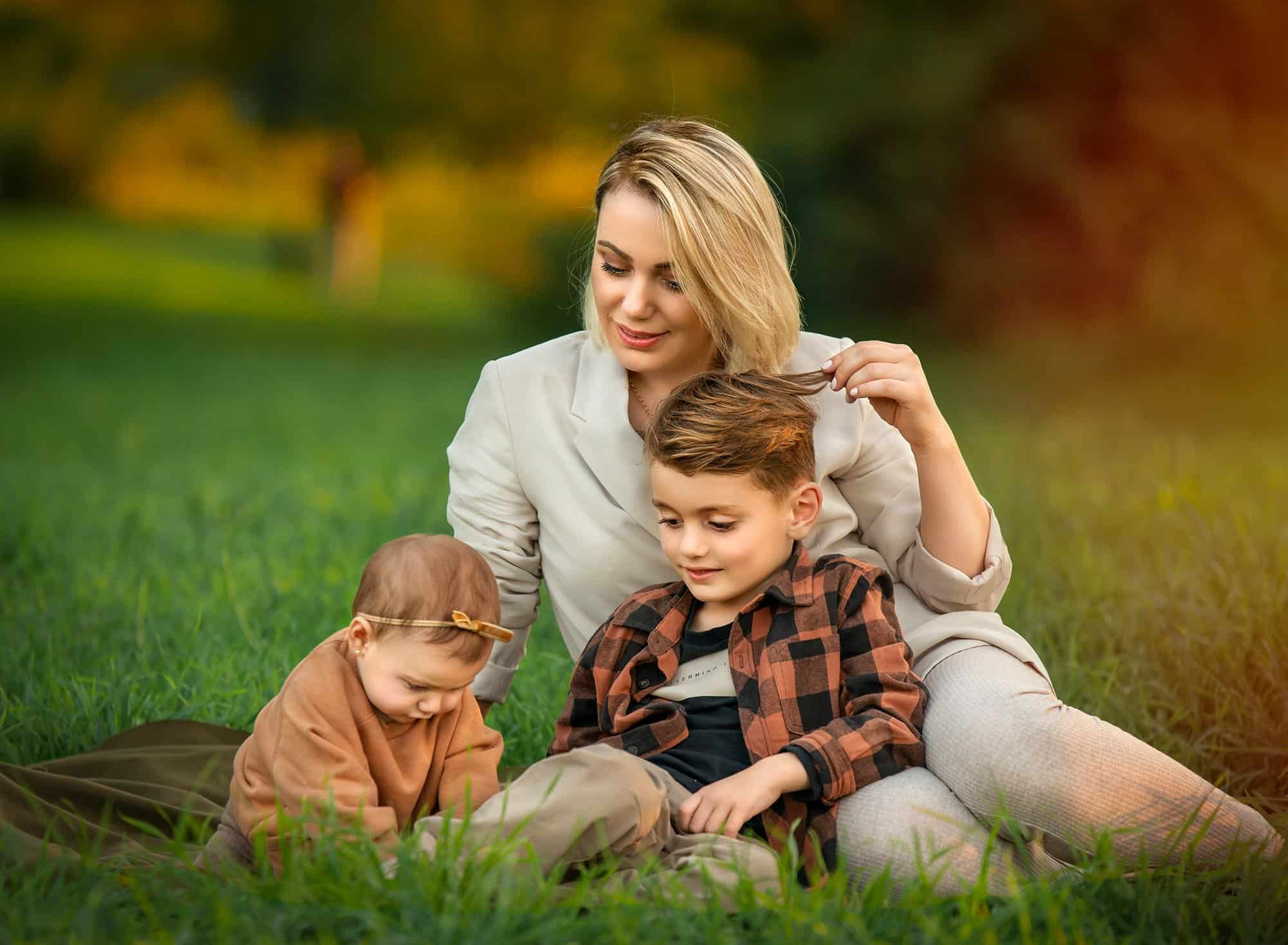 Outdoor family photoshoot in Glastonbury CT mother looking down at her son and daughter while sitting in nature